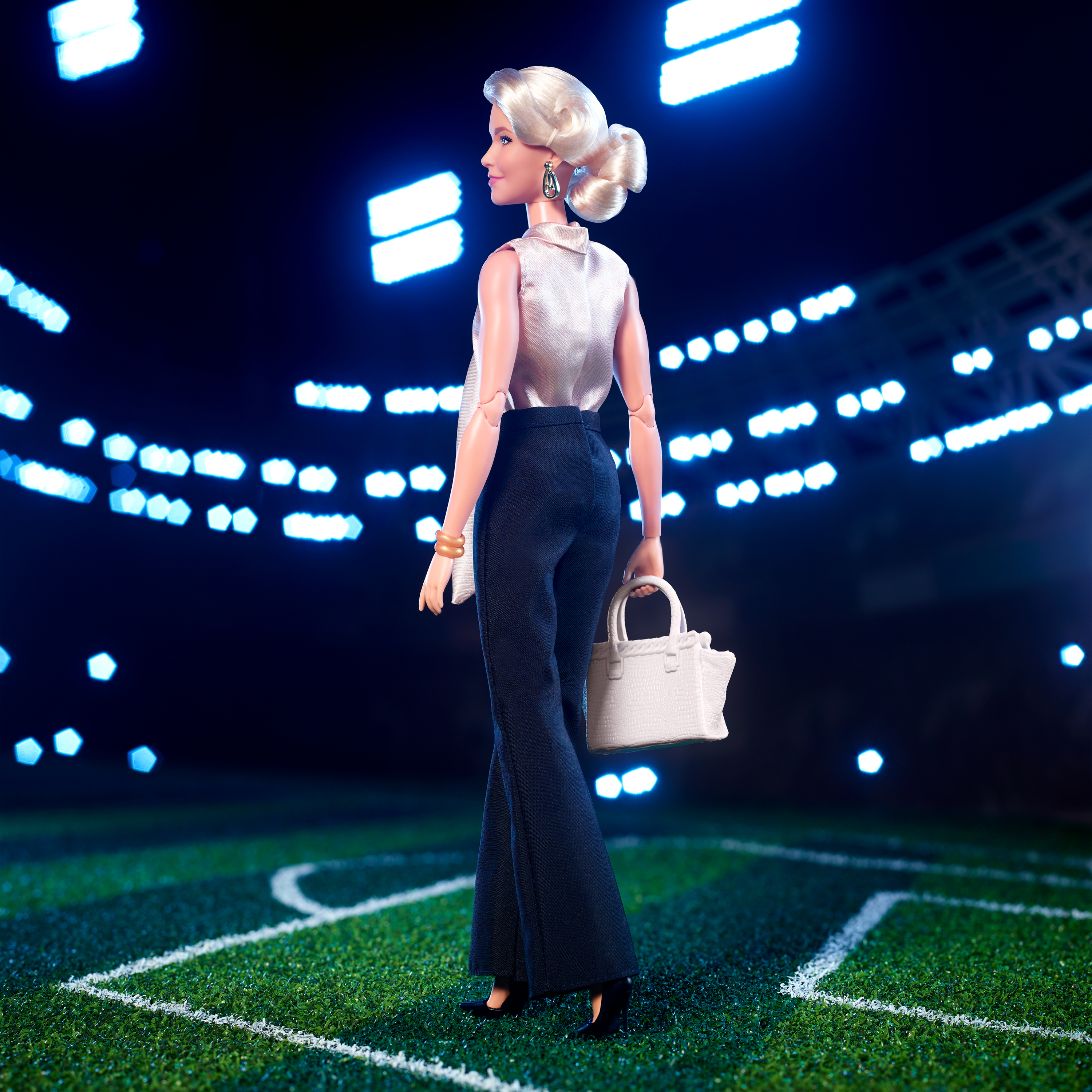 Eine Barbie-Puppe in einem Stadion, die ein stilvolles Outfit trägt.