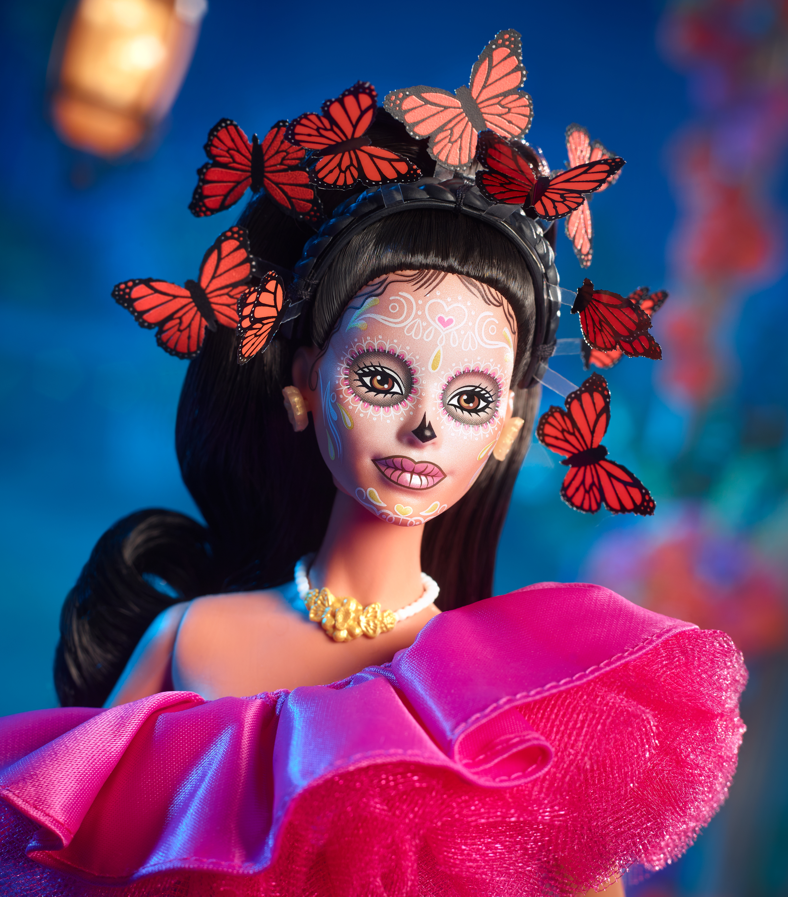 Eine Day-of-the-Dead-Barbie-Puppe mit Gesichtsbemalung, Schmetterlings-Kopfschmuck und einem rosa Kleid.
