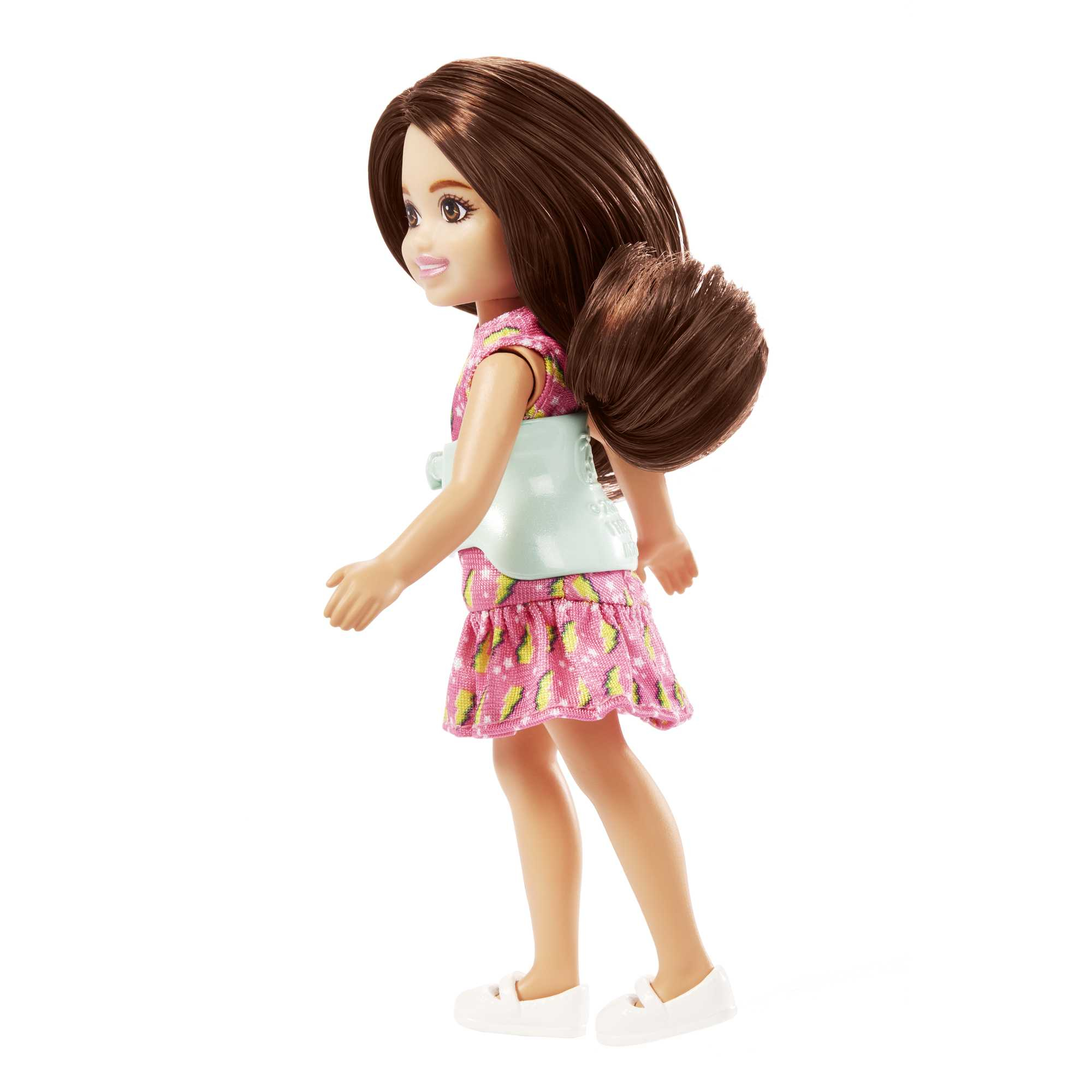 Puppe mit braunem Haar, rosa Kleid und weißen Schuhen, nach rechts auf weißem Hintergrund.