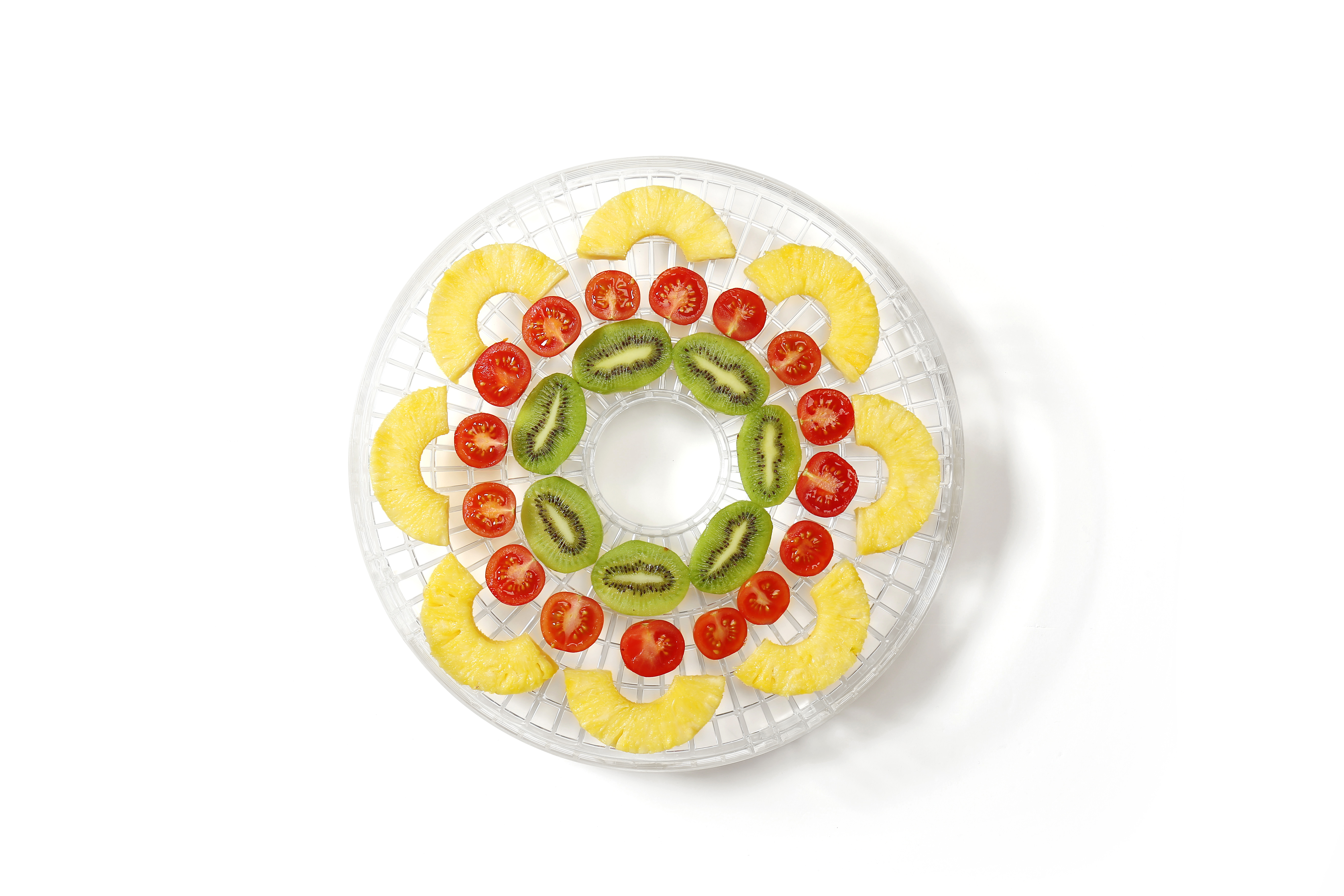 Ein transparentes Dörrgerät-Tablett mit Ananas-, Kiwi- und Cherrytomaten-Scheiben.