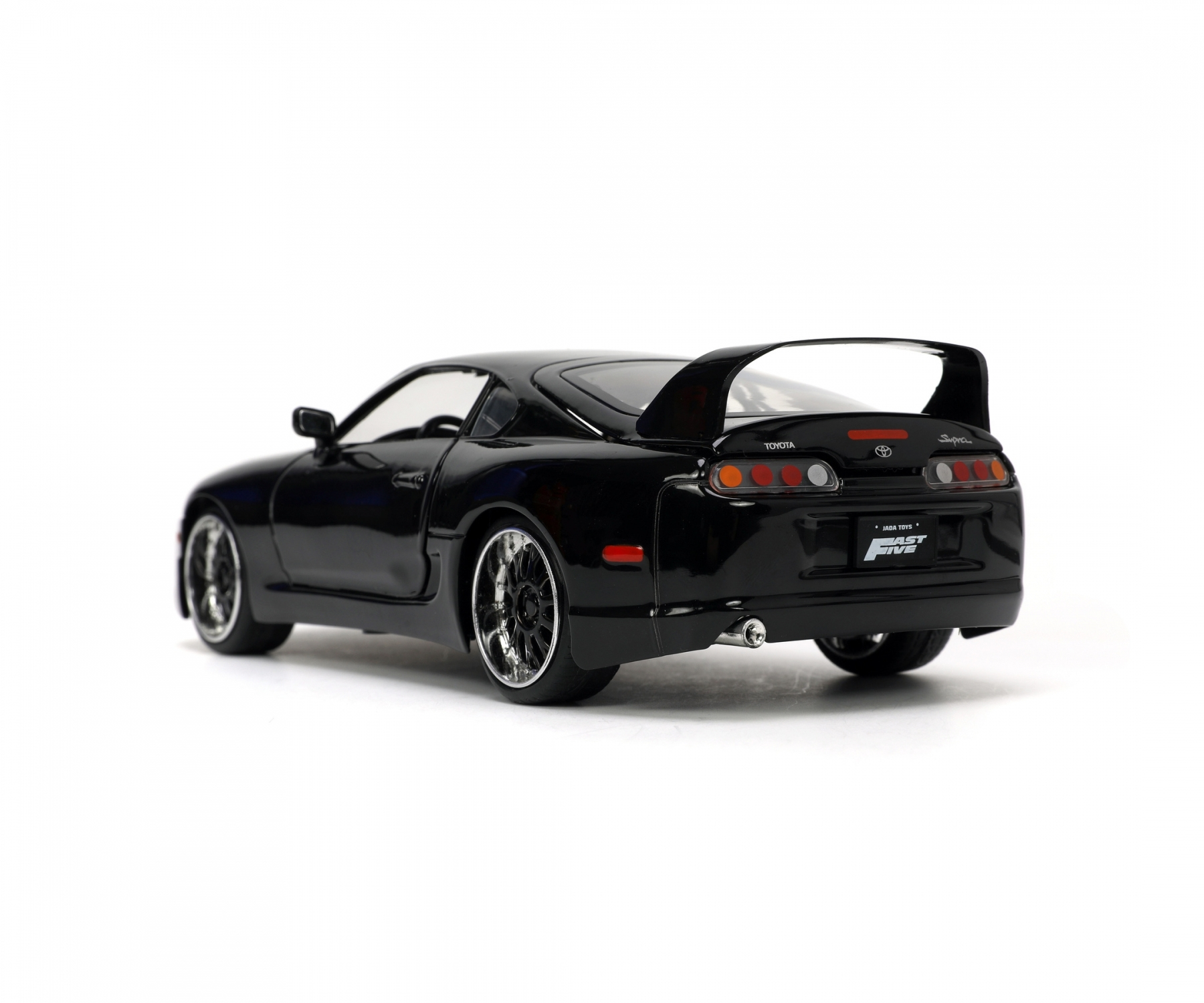 Schwarzes Spielzeugauto mit Spoiler. Das Auto steht auf einer weißen Oberfläche.