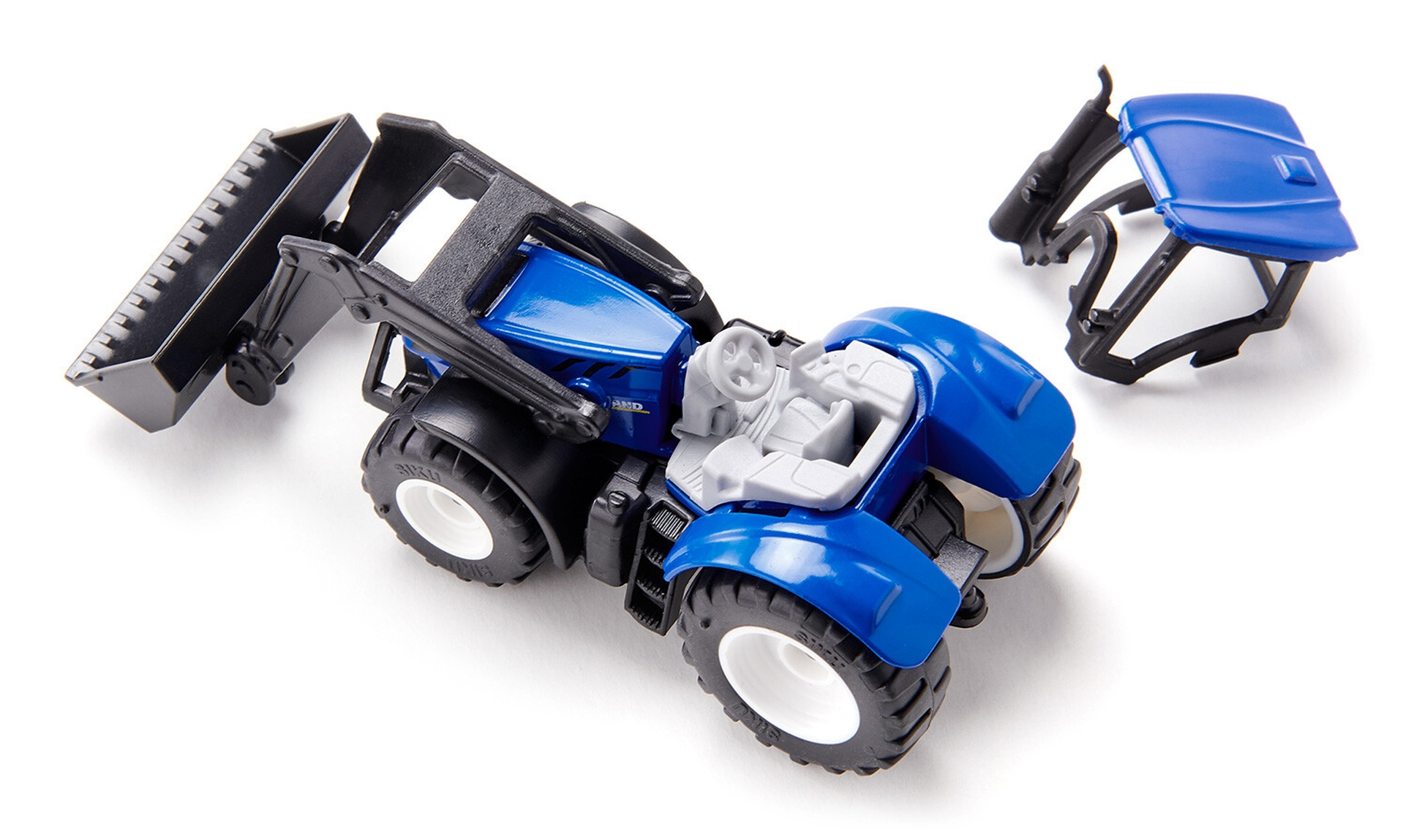 Niebieski traktor zabawka z czarną łyżką i odczepianą niebieską maską, na białym tle.