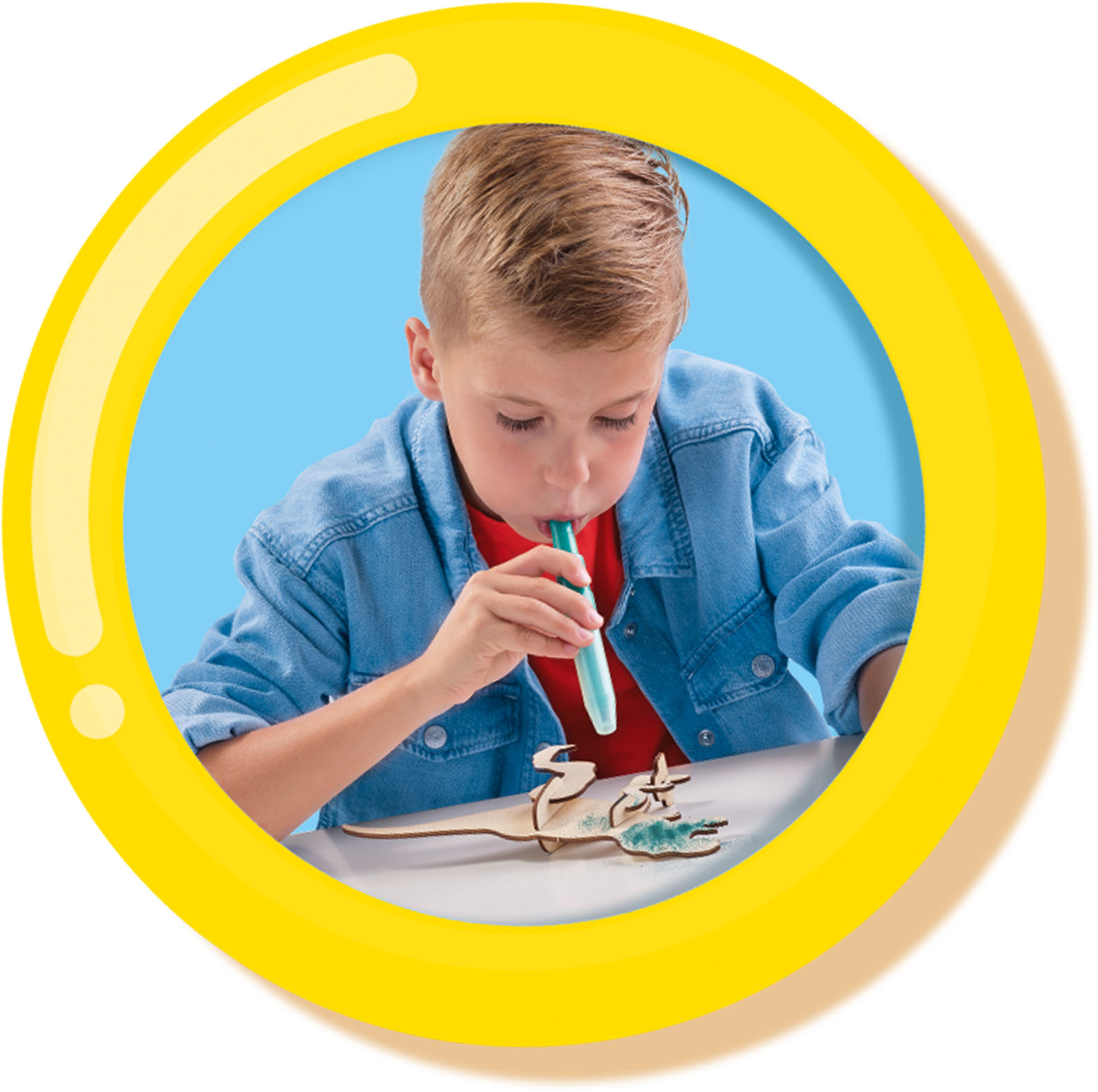 Chłopiec tworzy drewniany model w żółtej ramie, trzymając tubę do nakładania czegoś.