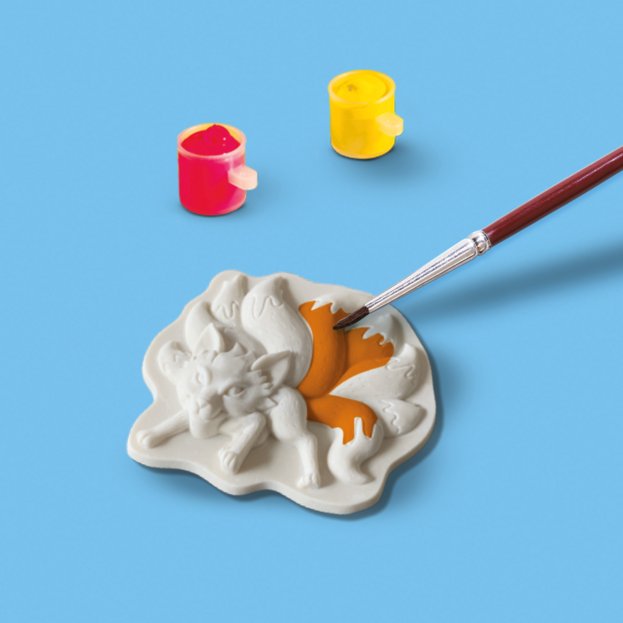 Pędzel malujący pomarańczowym kolorem białego lisa, z dwoma małymi słoiczkami farby.