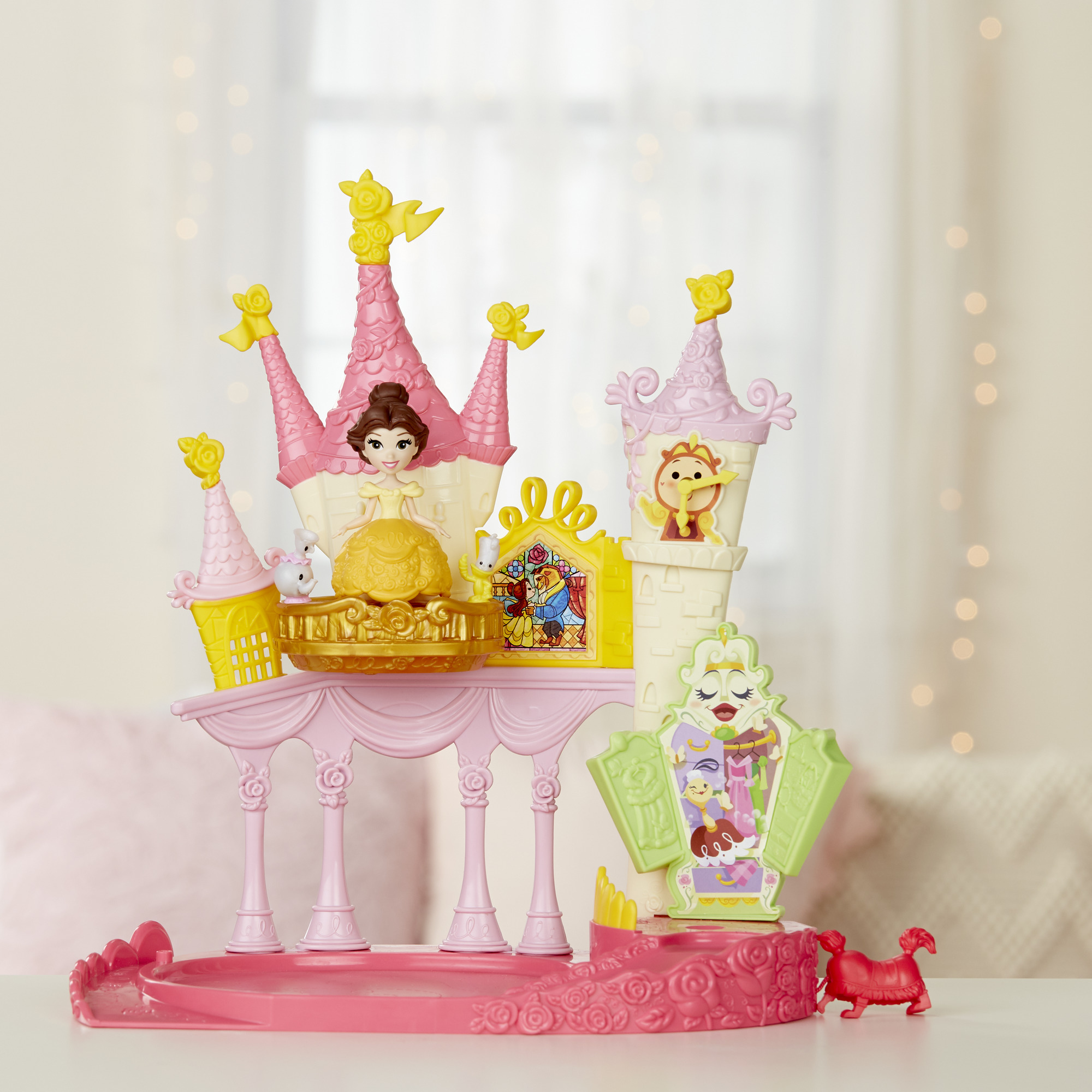 Un castello giocattolo de La Bella e la Bestia. È rosa e giallo con Belle e altre figure.