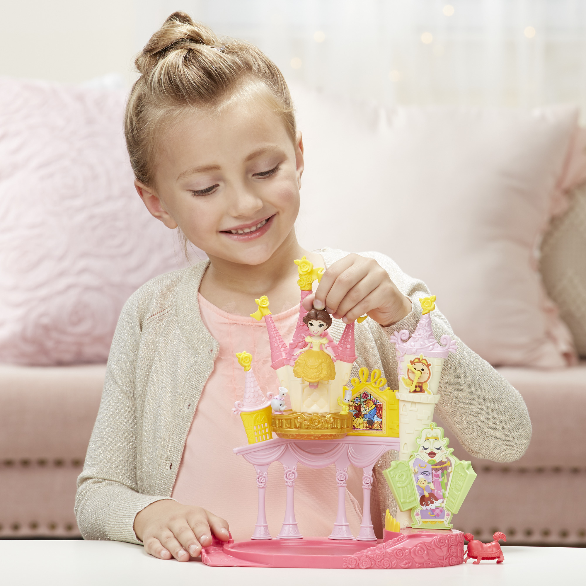 Una bambina gioca con un castello giocattolo de La Bella e la Bestia. Sta tenendo una piccola figura.