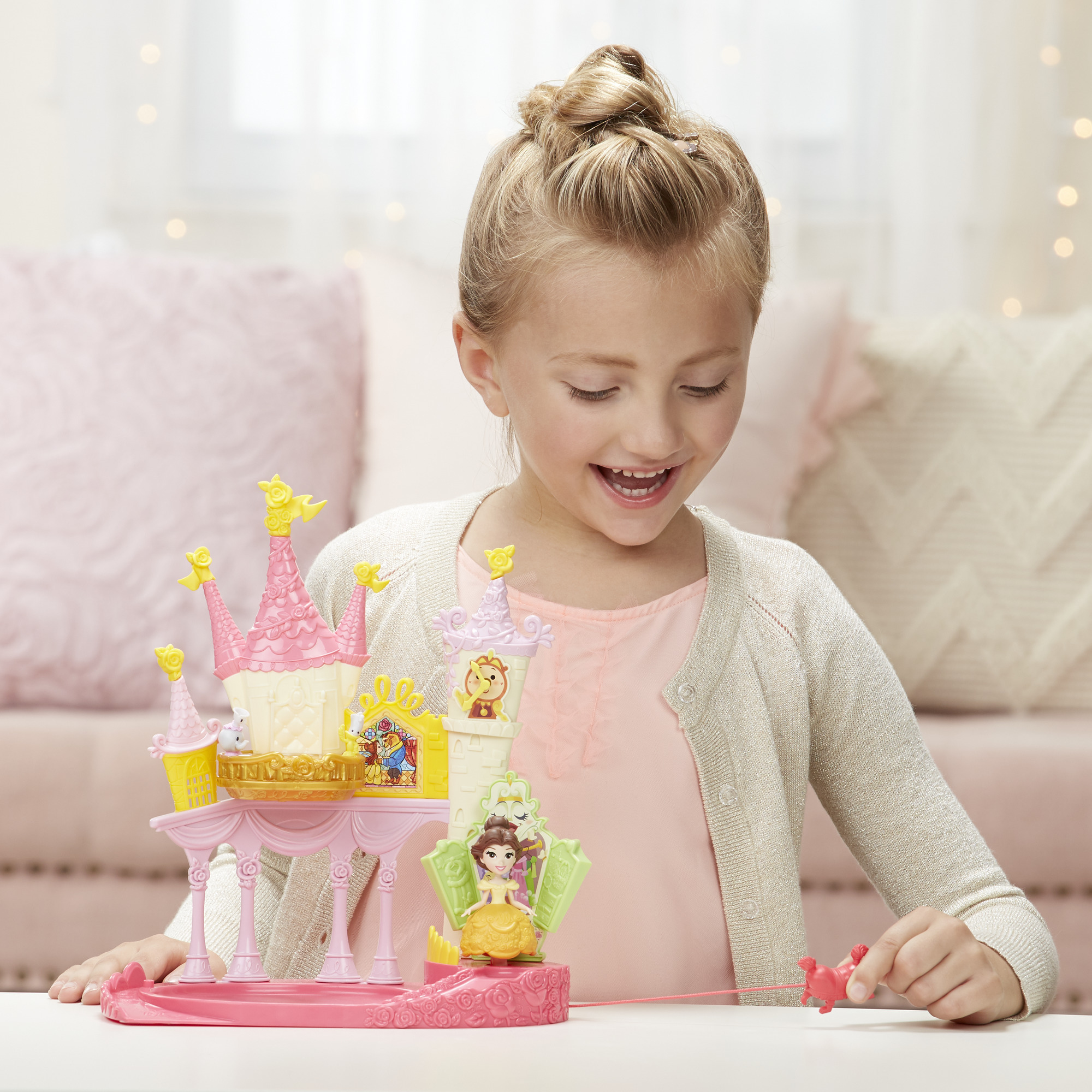 Una bambina gioca con un castello giocattolo de La Bella e la Bestia. Il castello è rosa e giallo.