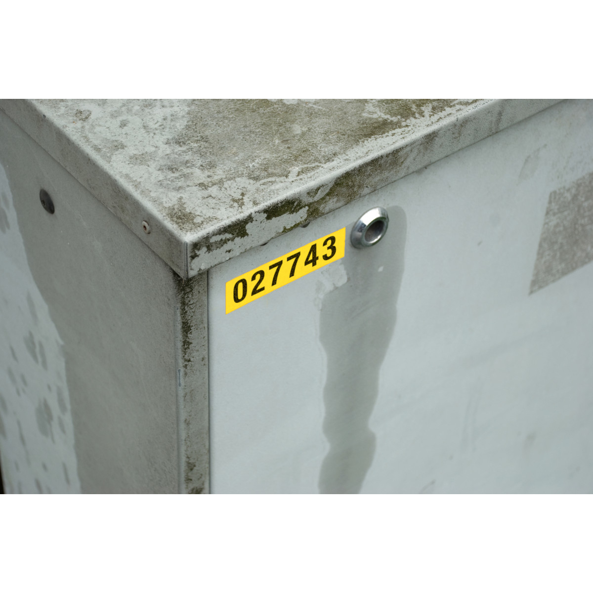 Una scatola di metallo con un'etichetta gialla con scritto '027743'.