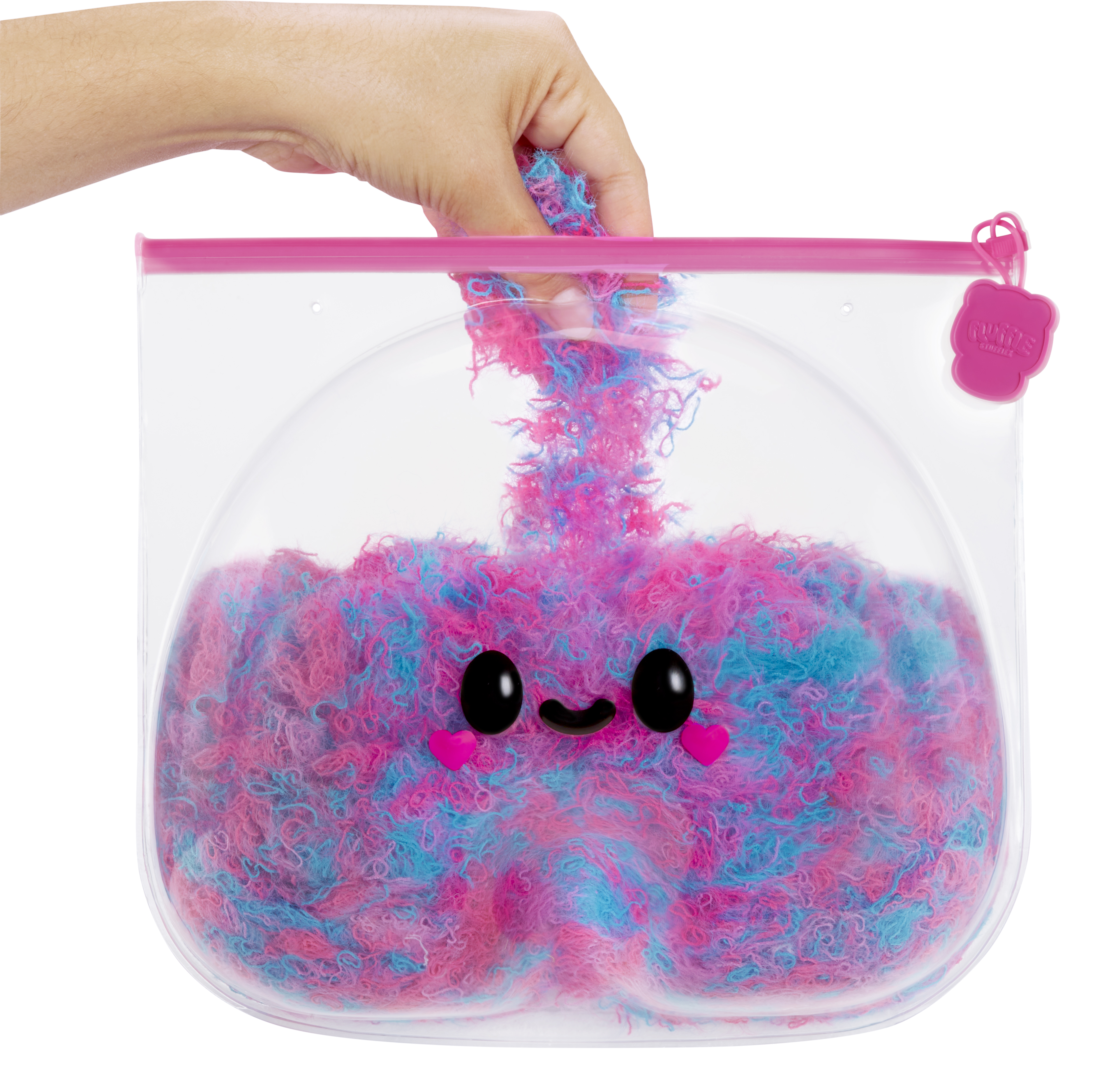 Przezroczysta plastikowa torba z puszystą zabawką w środku. Różowa i niebieska z uśmiechniętą buzią.
