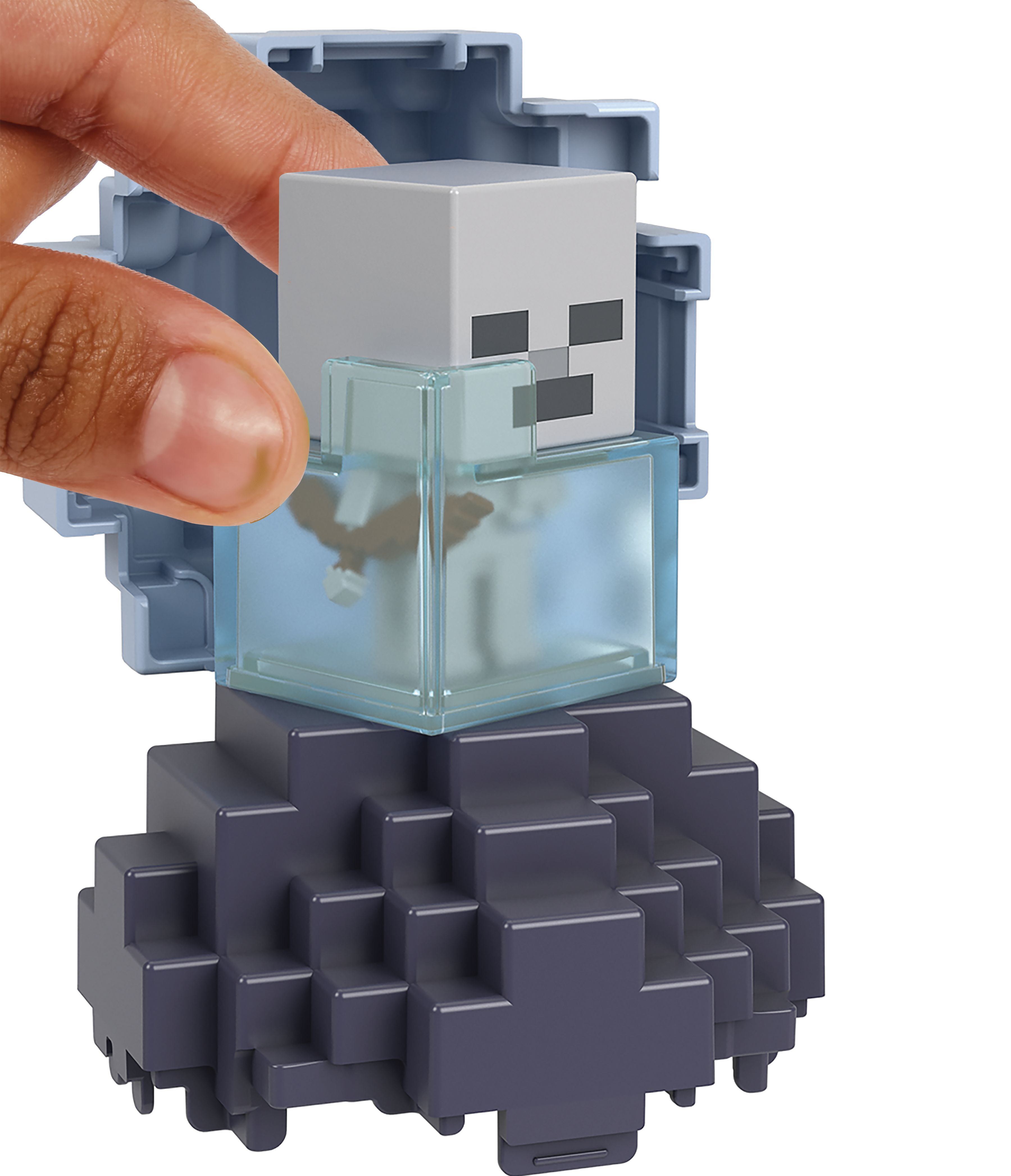 Dłoń trzymająca figurkę szkieletu Minecraft, z ciemnoniebieską podstawą i przezroczystą kostką.