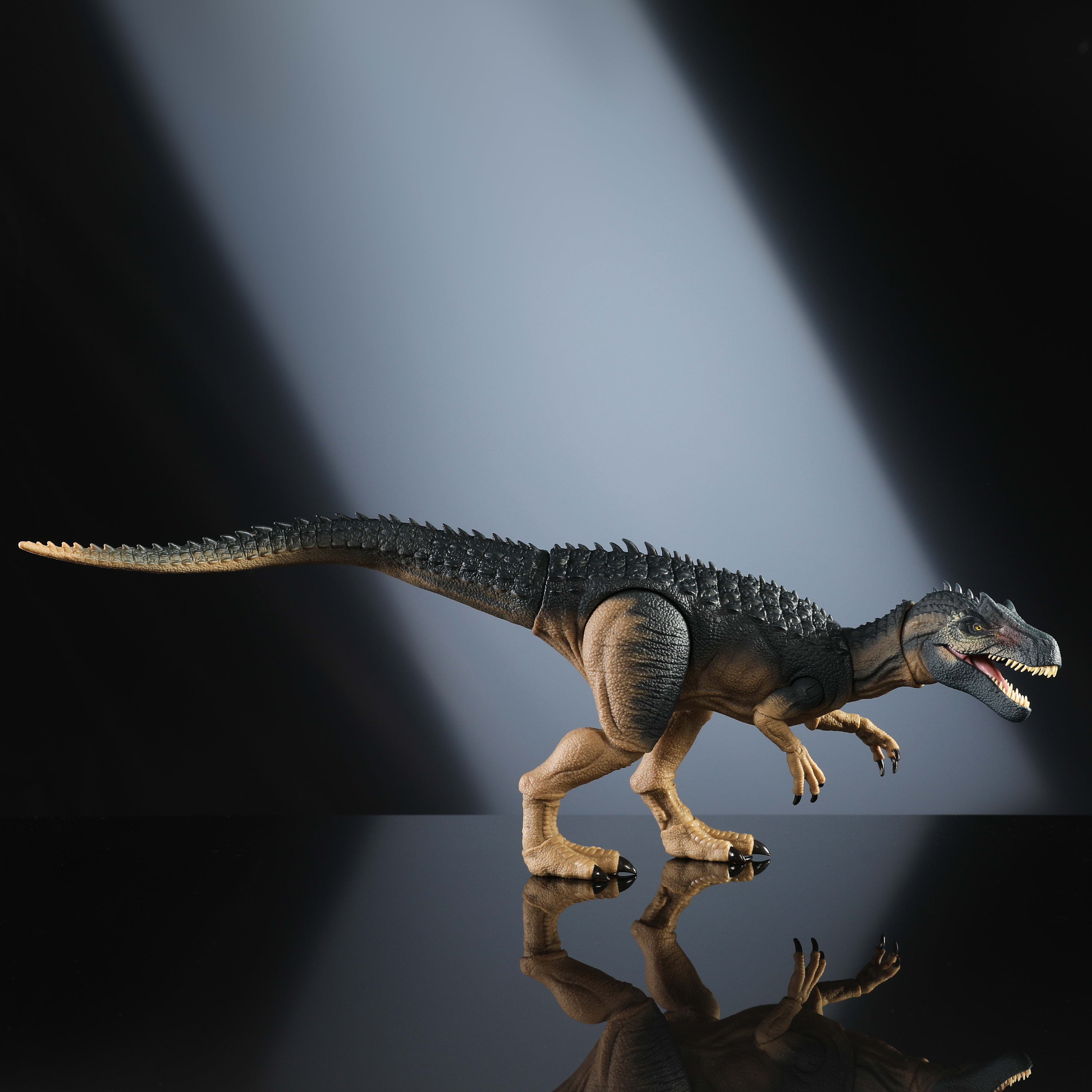 Giocattolo di dinosauro con corpo marrone e nero, su superficie riflettente.