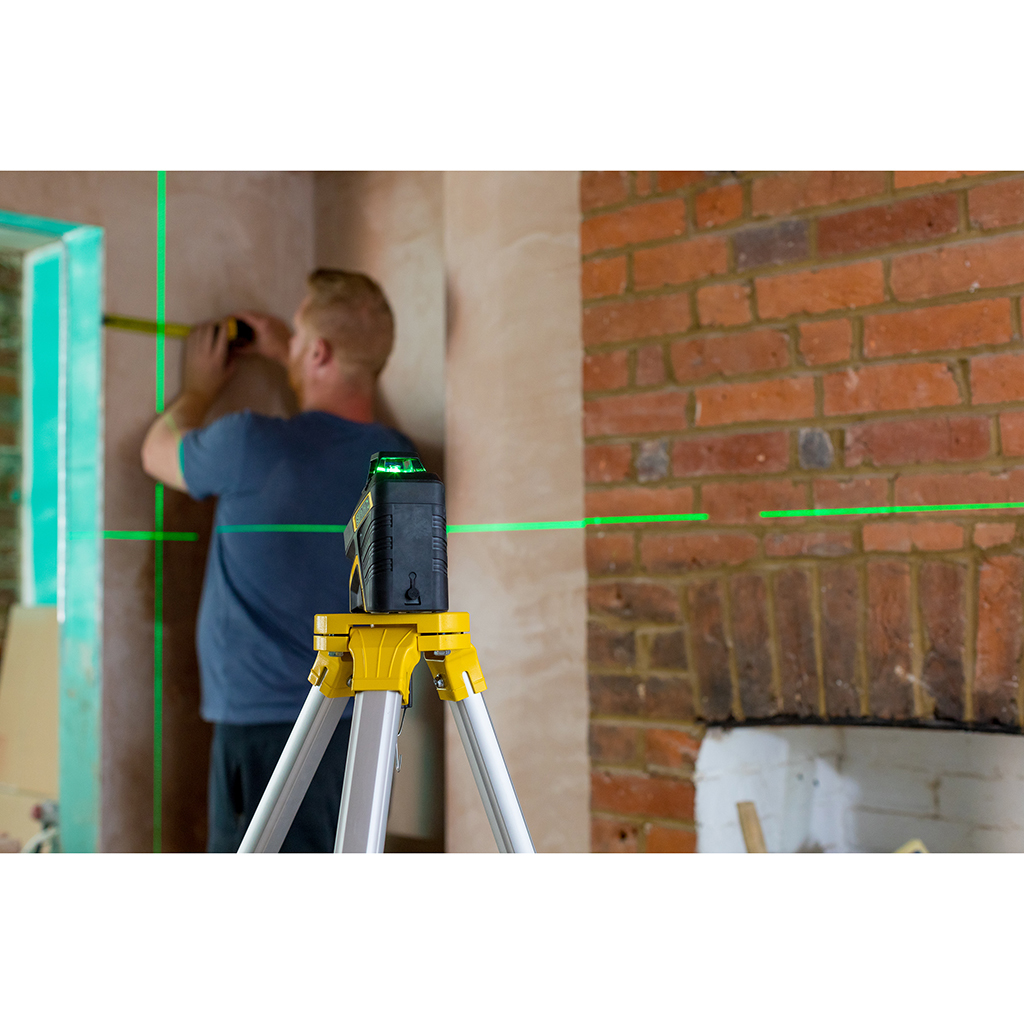 Ein Mann, der ein Laser-Niveau zur Wandmessung verwendet. Grüne Laserlinien sichtbar.