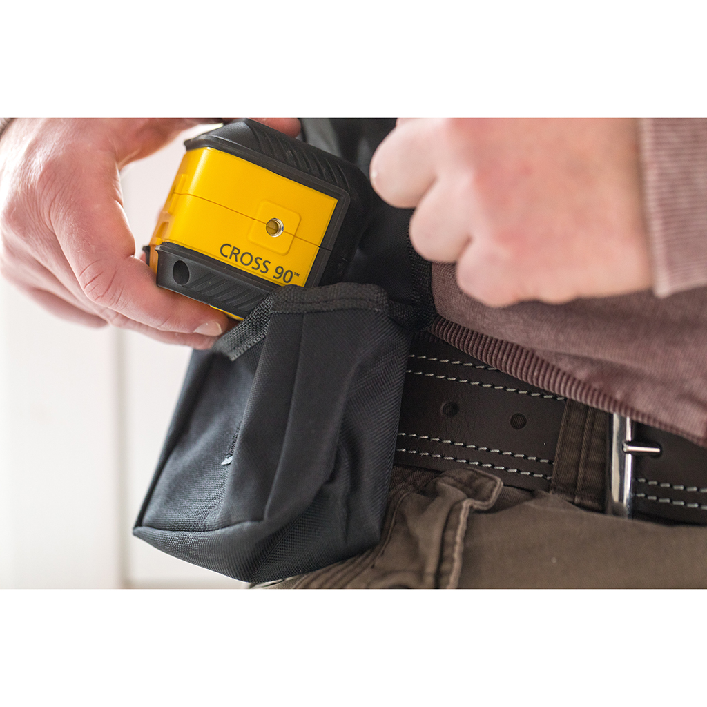 Eine Person, die einen gelben Laserpegel in eine schwarze Werkzeugtasche legt.