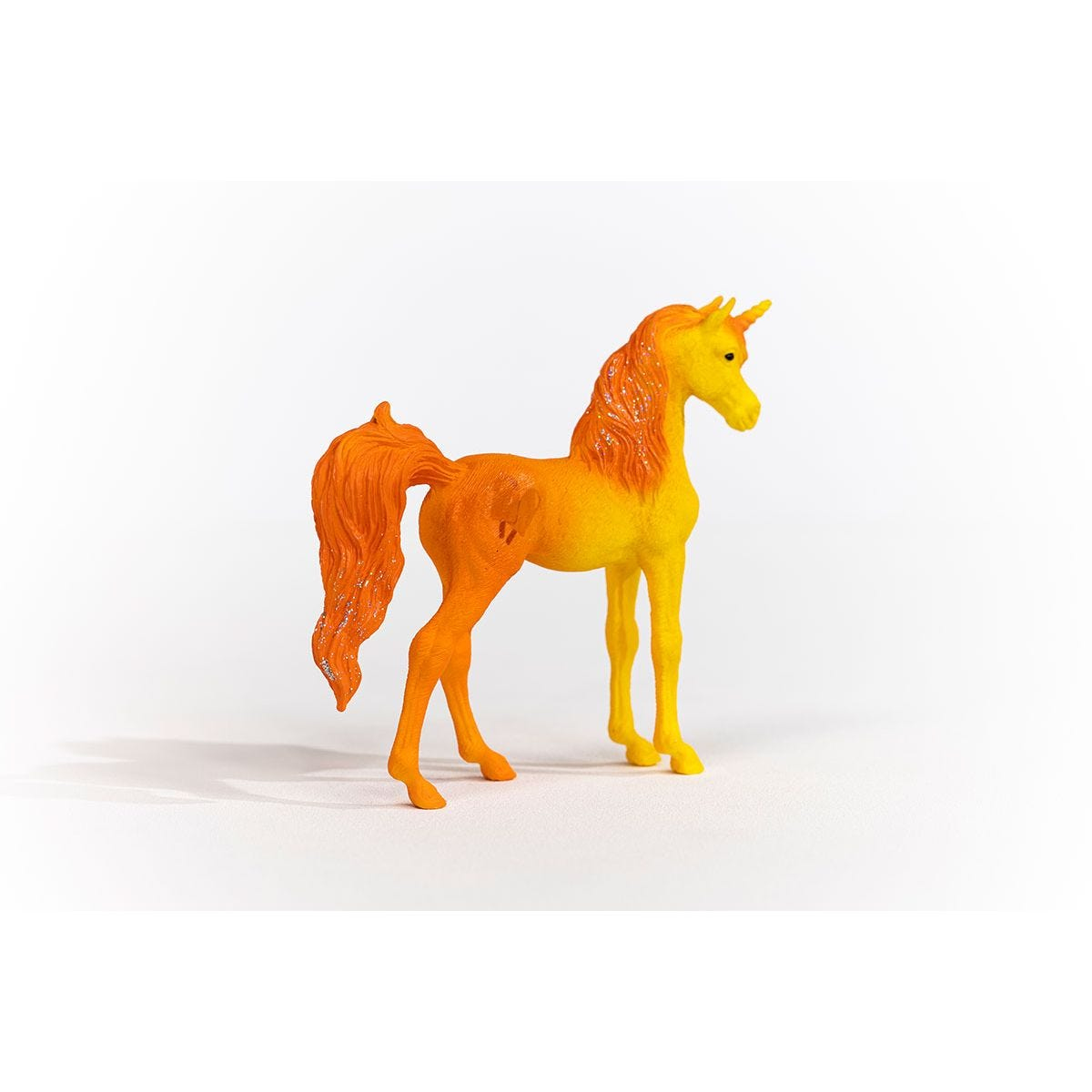Ein Spielzeug-Einhorn mit orangefarbenem Körper und Mähne. Es steht auf einer weißen Oberfläche.