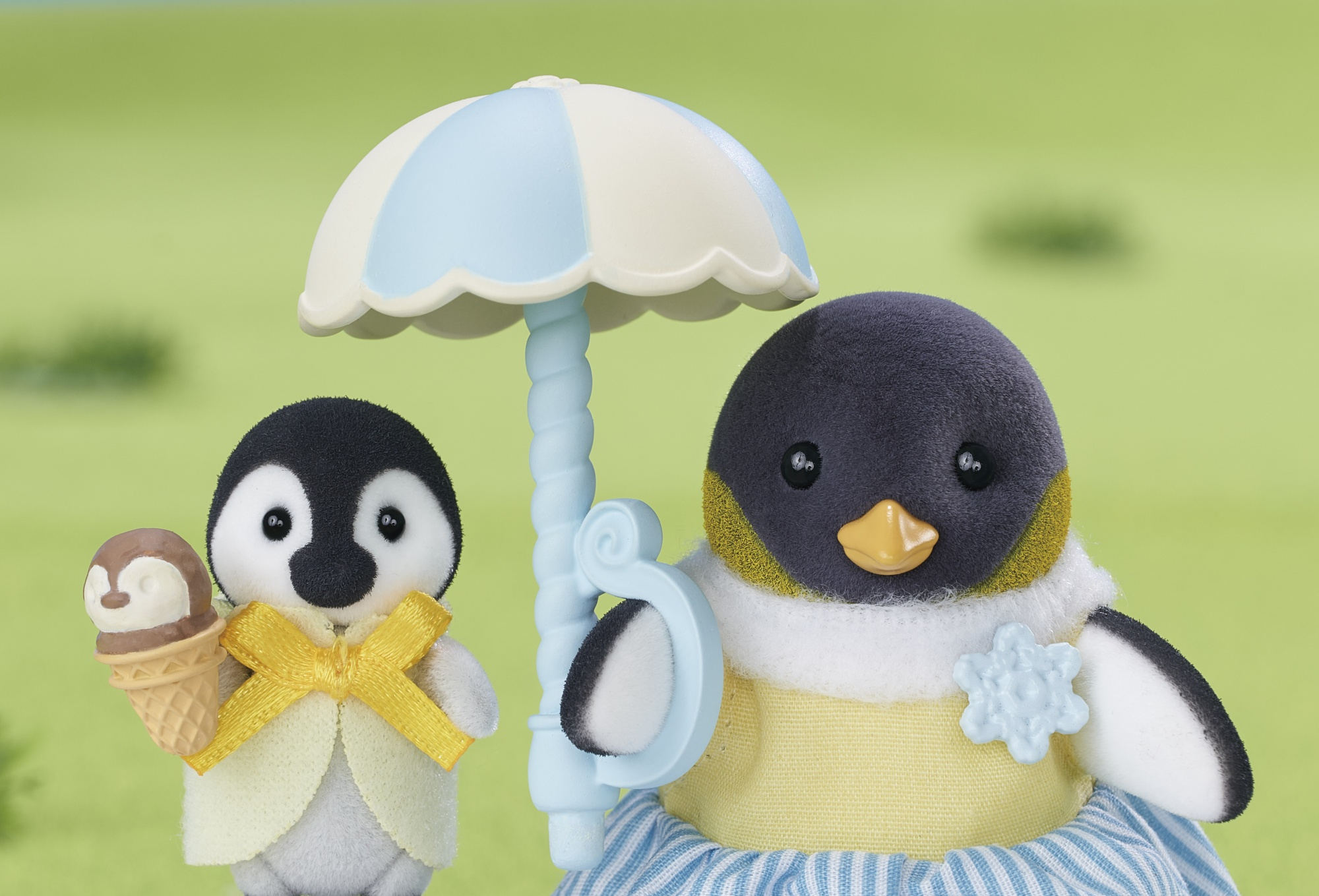 Dos pingüinos con un helado y un parasol. El fondo es verde.