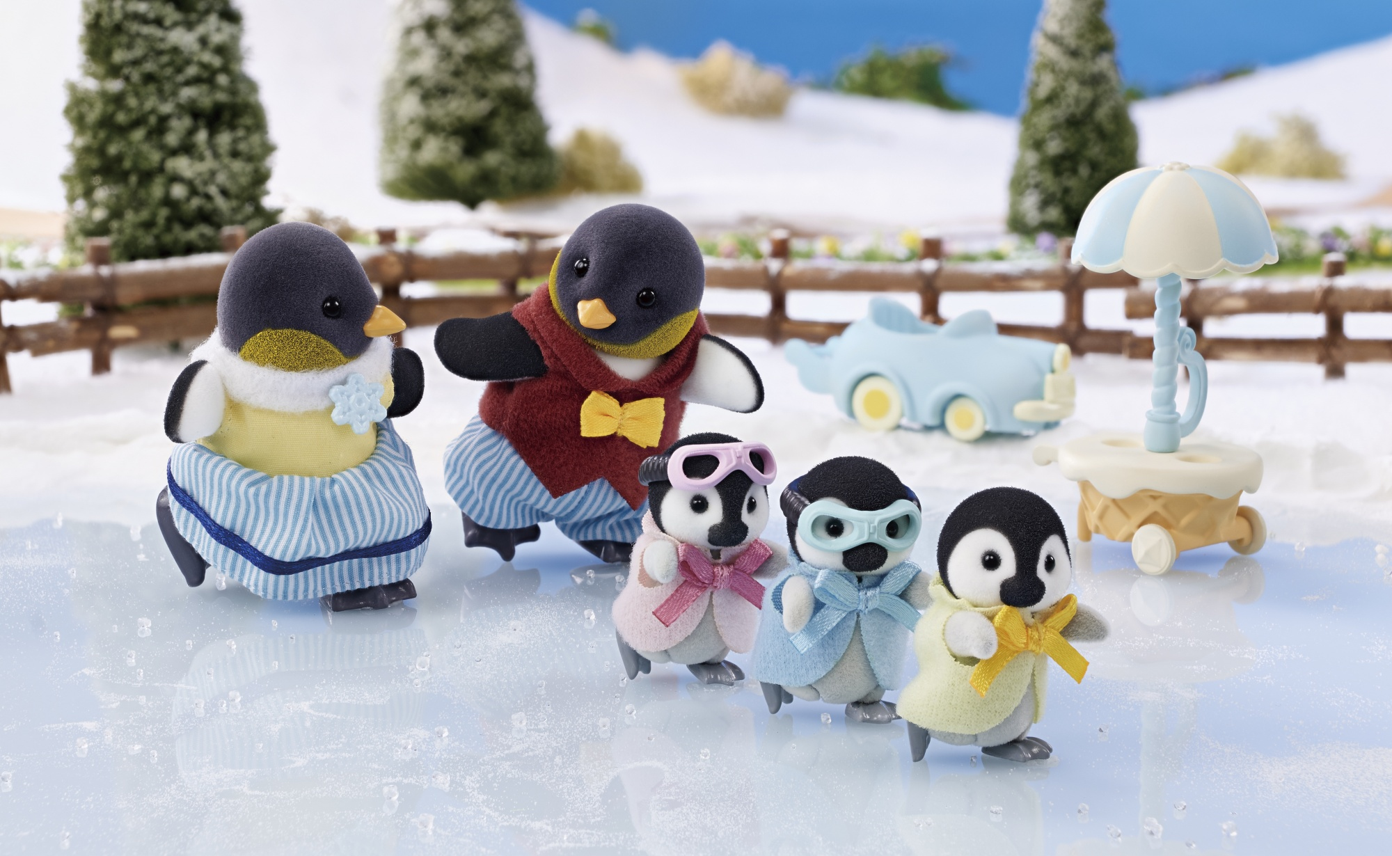 Figuras de familia de pingüinos en una pista de hielo. Pingüinos con sombreros, bufandas y un avión de juguete.