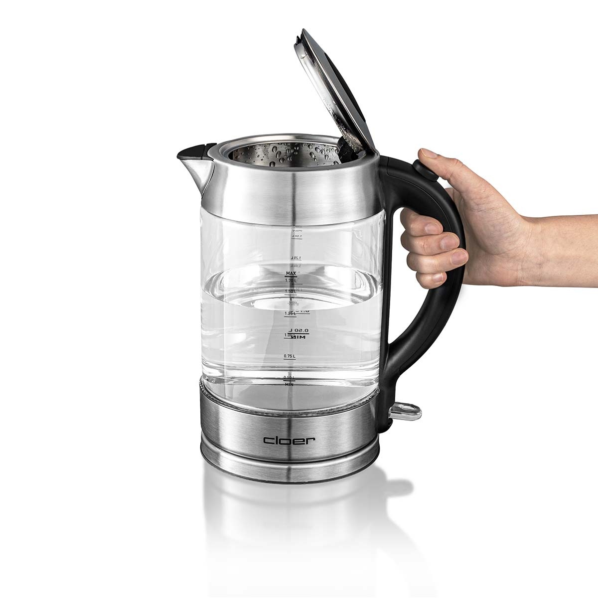 Szklany czajnik. Ręka trzyma uchwyt. Płyta podstawy poniżej. Woda wewnątrz.