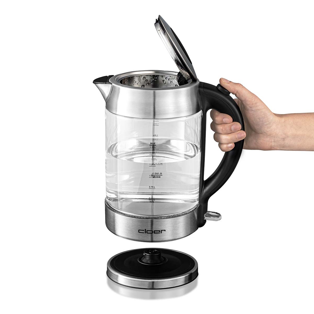 Szklany czajnik. Ręka trzyma uchwyt. Płyta podstawy poniżej. Woda wewnątrz.