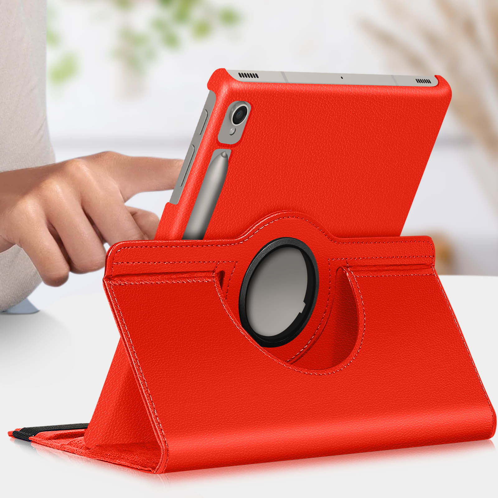 Custodia per tablet rossa con tablet. Il tablet ha lo stilo. La custodia ha un supporto rotante. Mano a sinistra.