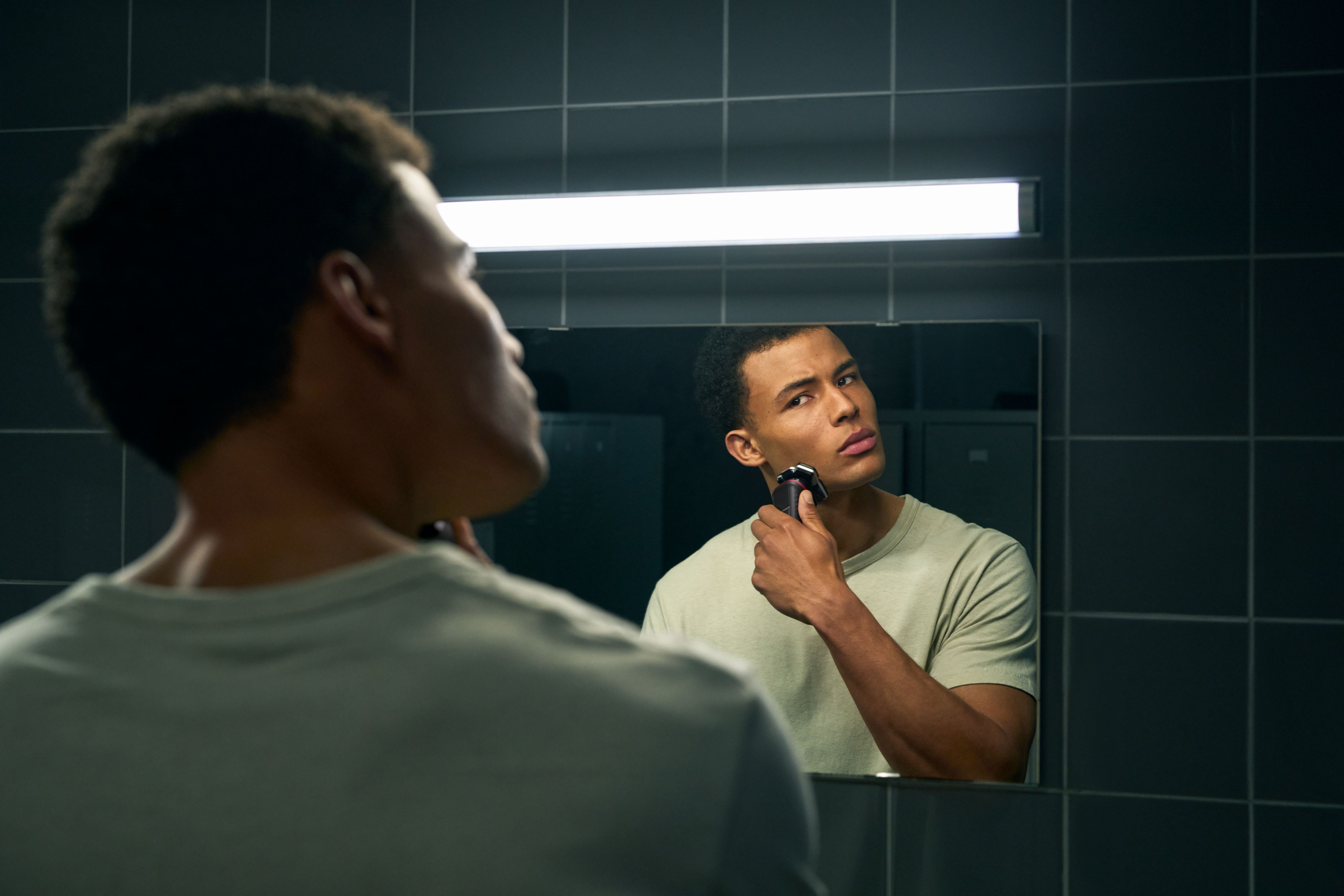 Mężczyzna goli się w lustrze golarką Philips w łazience.