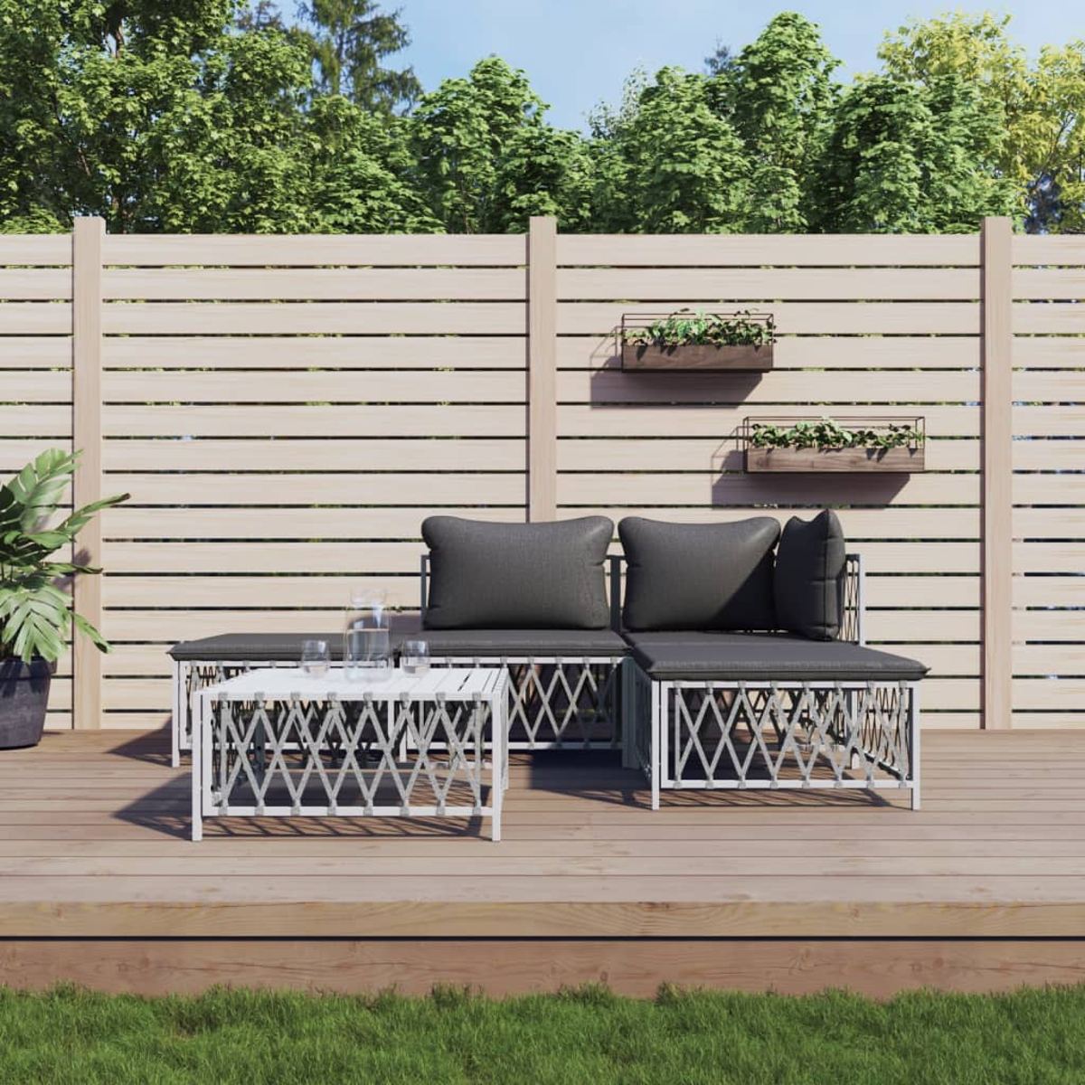 Gartenmöbel. Graue Kissen, weiße Möbel, Holzterrasse und ein heller Holzzaun im Hintergrund.