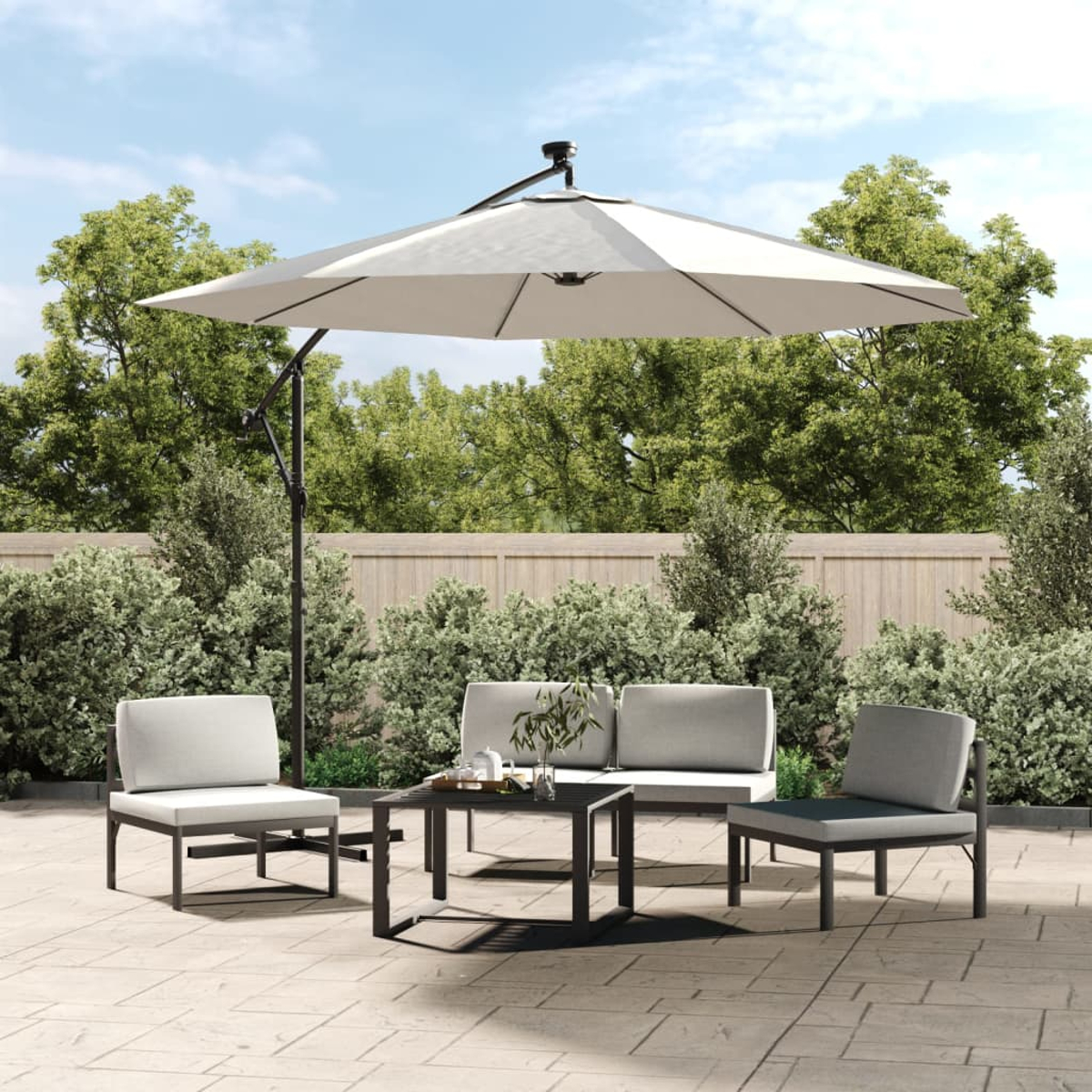 Terrasse mit Outdoor-Möbelset, Sonnenschirm, Pflanzen und weißem Zaun.