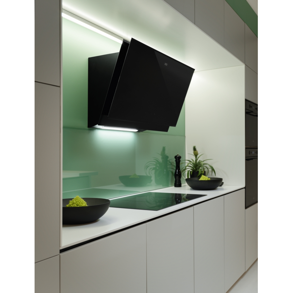 Cucina moderna con parete verde, piano cottura nero e ciotole. Il design è minimalista.