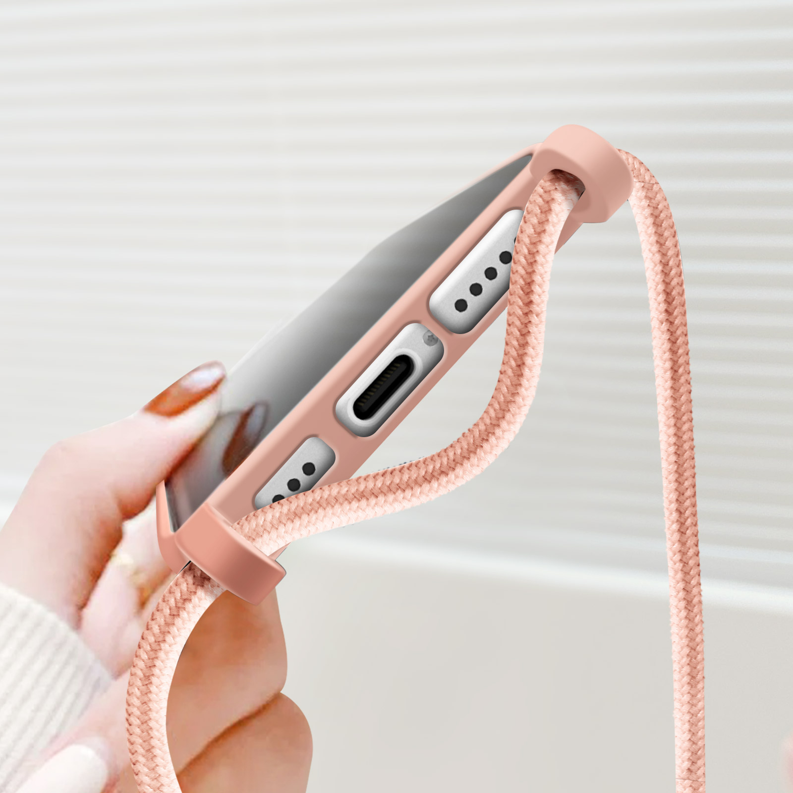 Custodia per telefono rosa con cordino rosa tenuto da una mano.
