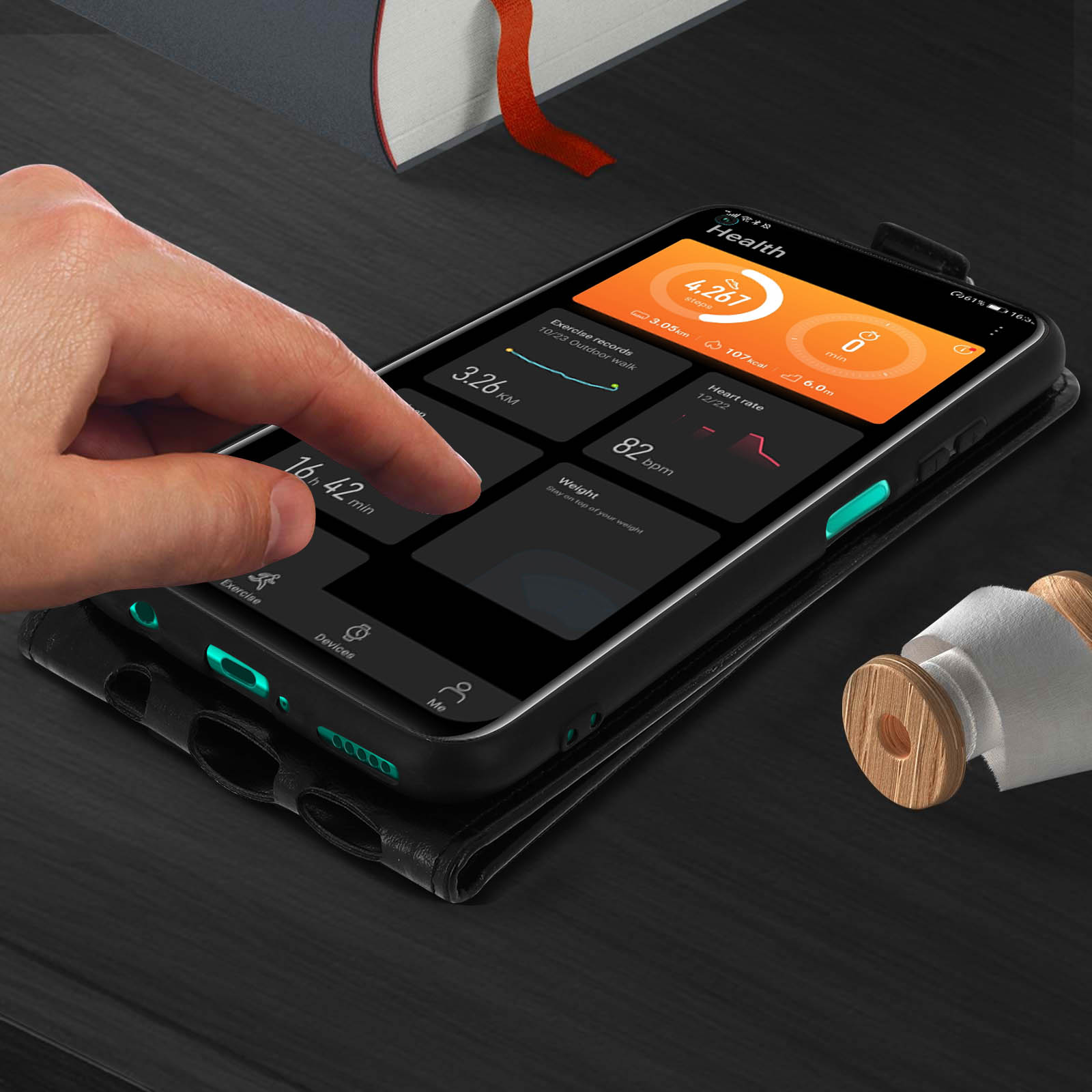 Telefono che mostra l'app salute. Mano che tocca lo schermo. Libro e oggetto in legno sullo sfondo.