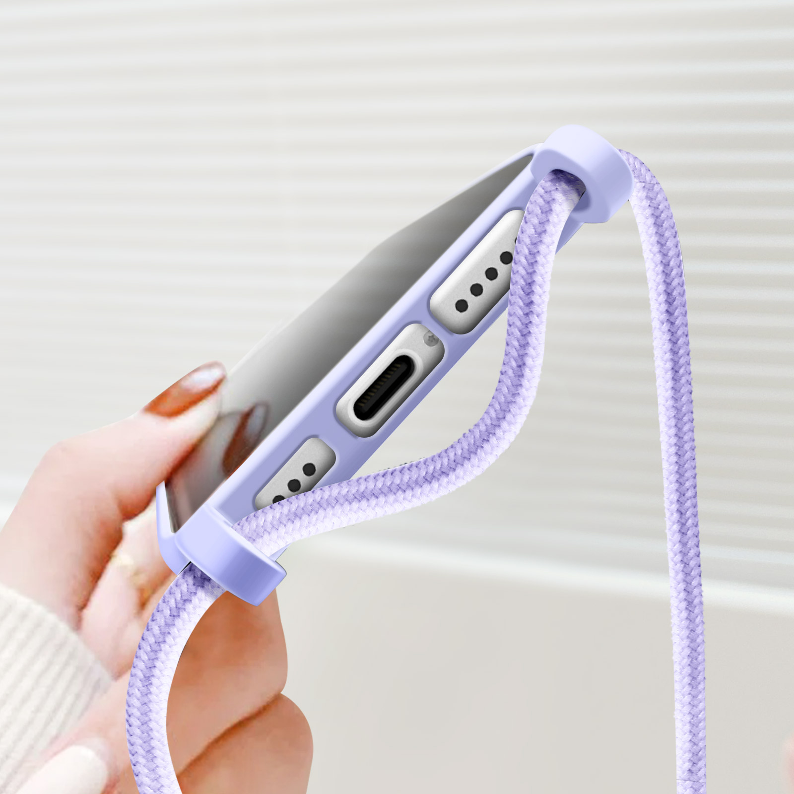 Una mano che tiene una custodia per telefono. La custodia è viola e ha un cordino viola.