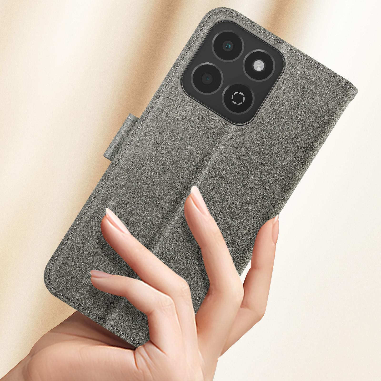 Mano che tiene una custodia grigia per telefono con telefono all'interno. Il telefono ha quattro fotocamere.