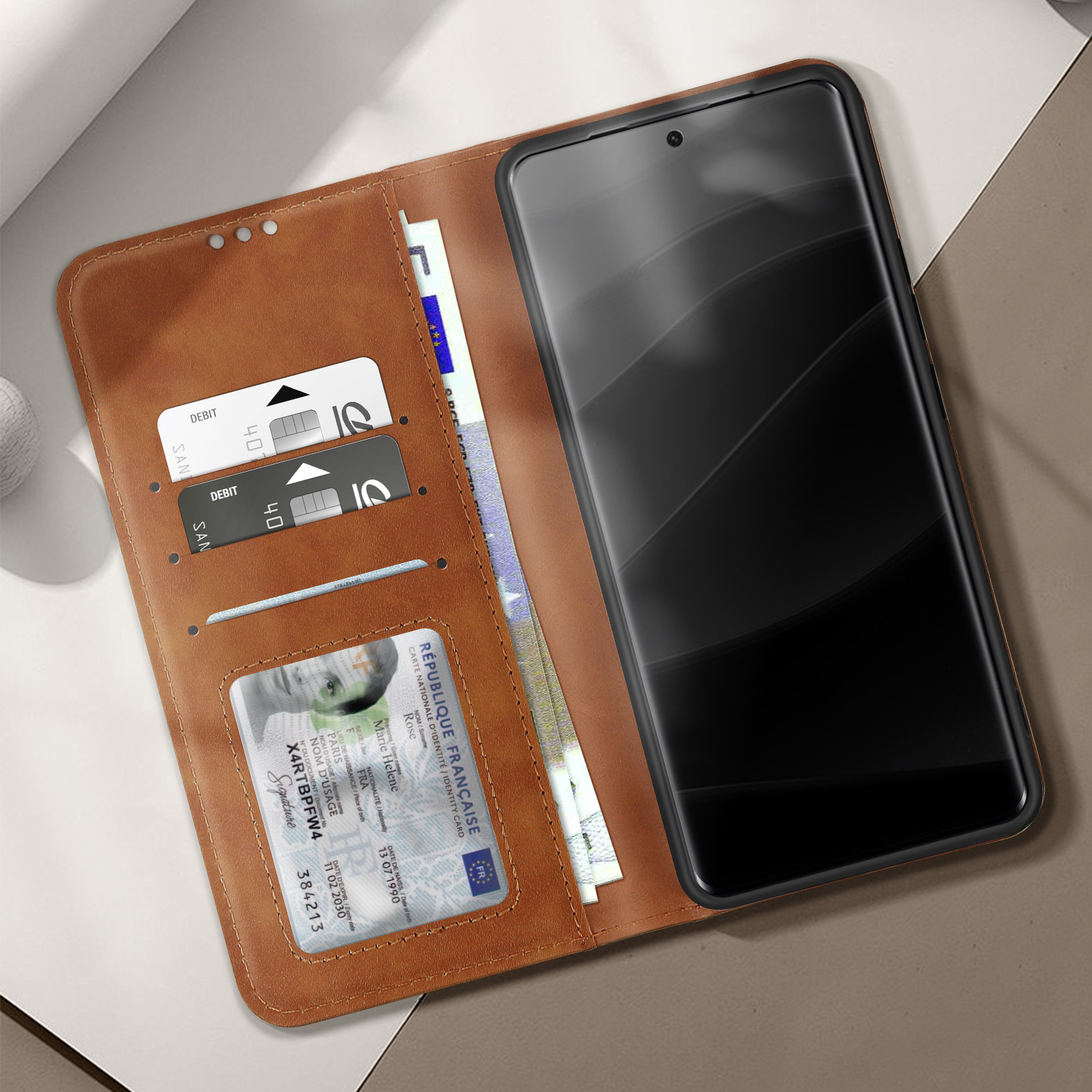 Una custodia per telefono in pelle marrone aperta, che mostra carte e un telefono. Una carta di debito e un documento d'identità sono visibili.
