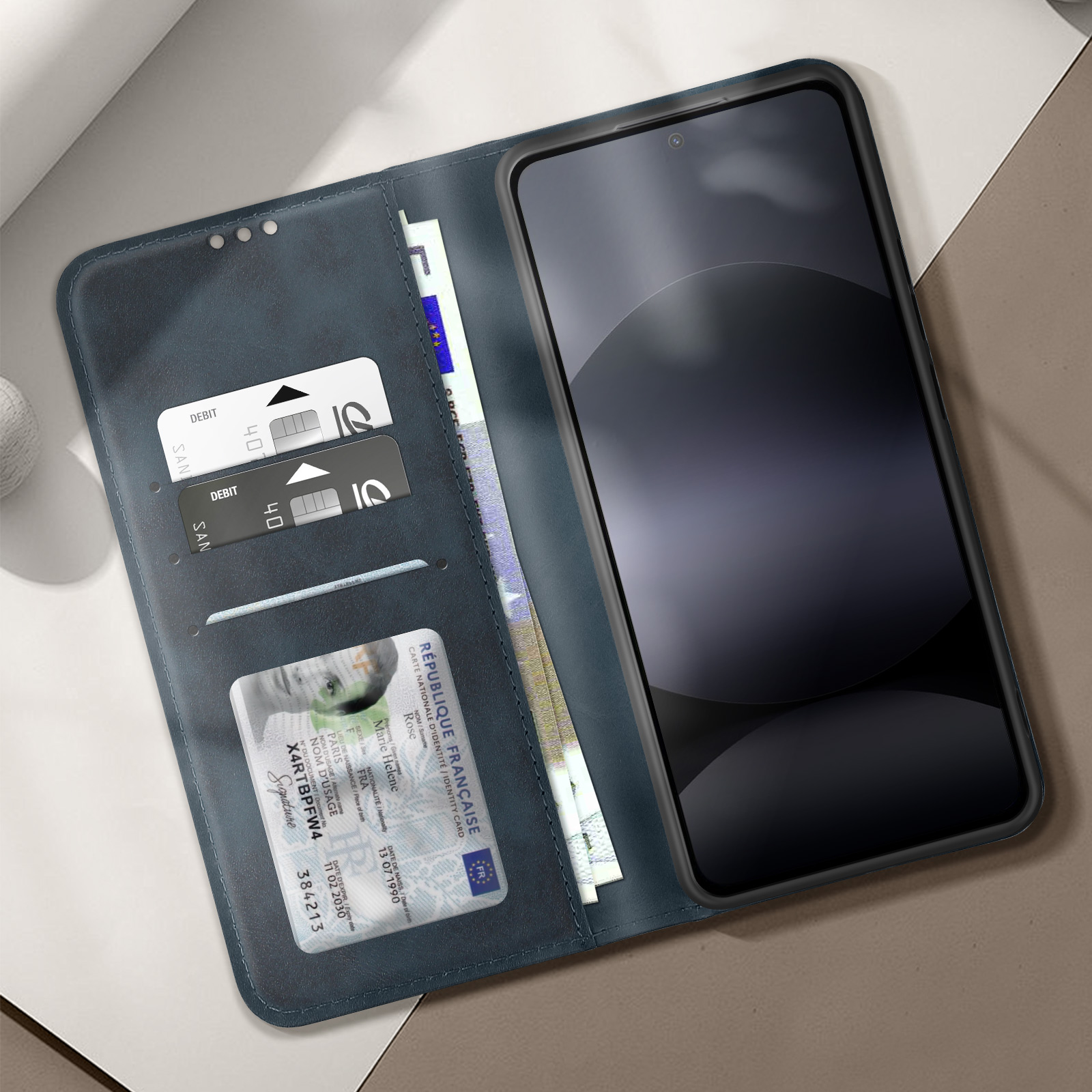 Custodia blu per telefono aperta, che mostra carte, denaro e telefono con schermo nero.