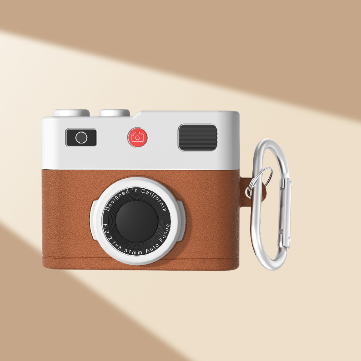 Custodia a forma di fotocamera con parte anteriore marrone, parte superiore bianca e moschettone argentato. Bottone rosso.