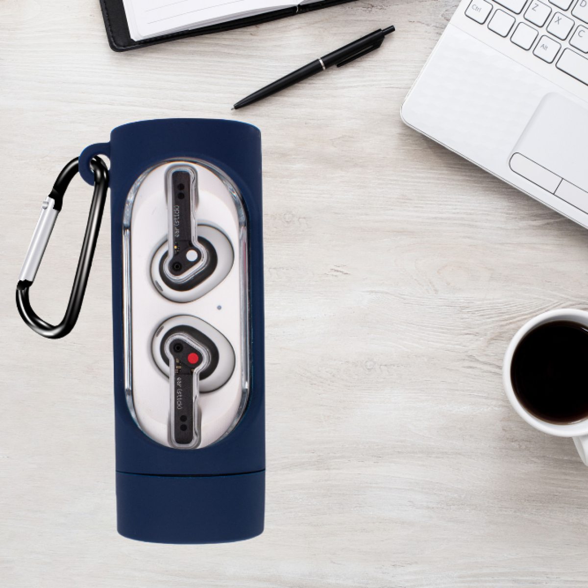 Auricolari in una custodia blu con moschettone nero, su una scrivania con laptop e penna.