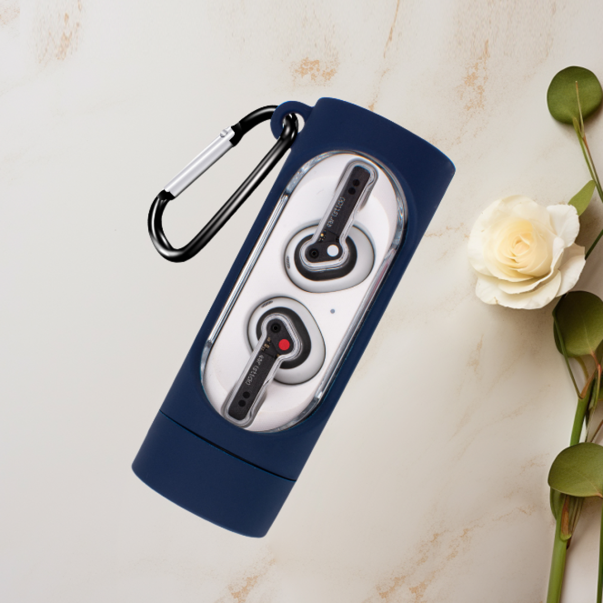 Auricolari in custodia blu con moschettone, su marmo, vicino a rosa e foglie.