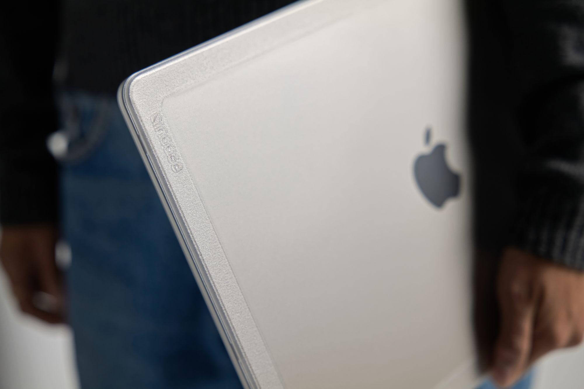 Primo piano di un laptop argentato tenuto da una persona. I loghi Apple e Incase sono visibili.