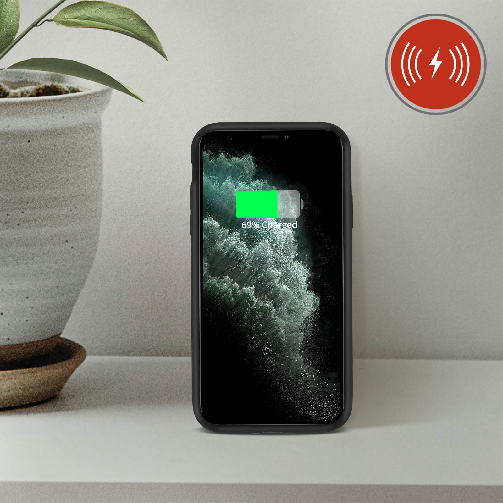 Telefono nero in carica wireless su una superficie bianca. Un'icona della batteria verde mostra il 69% di carica.
