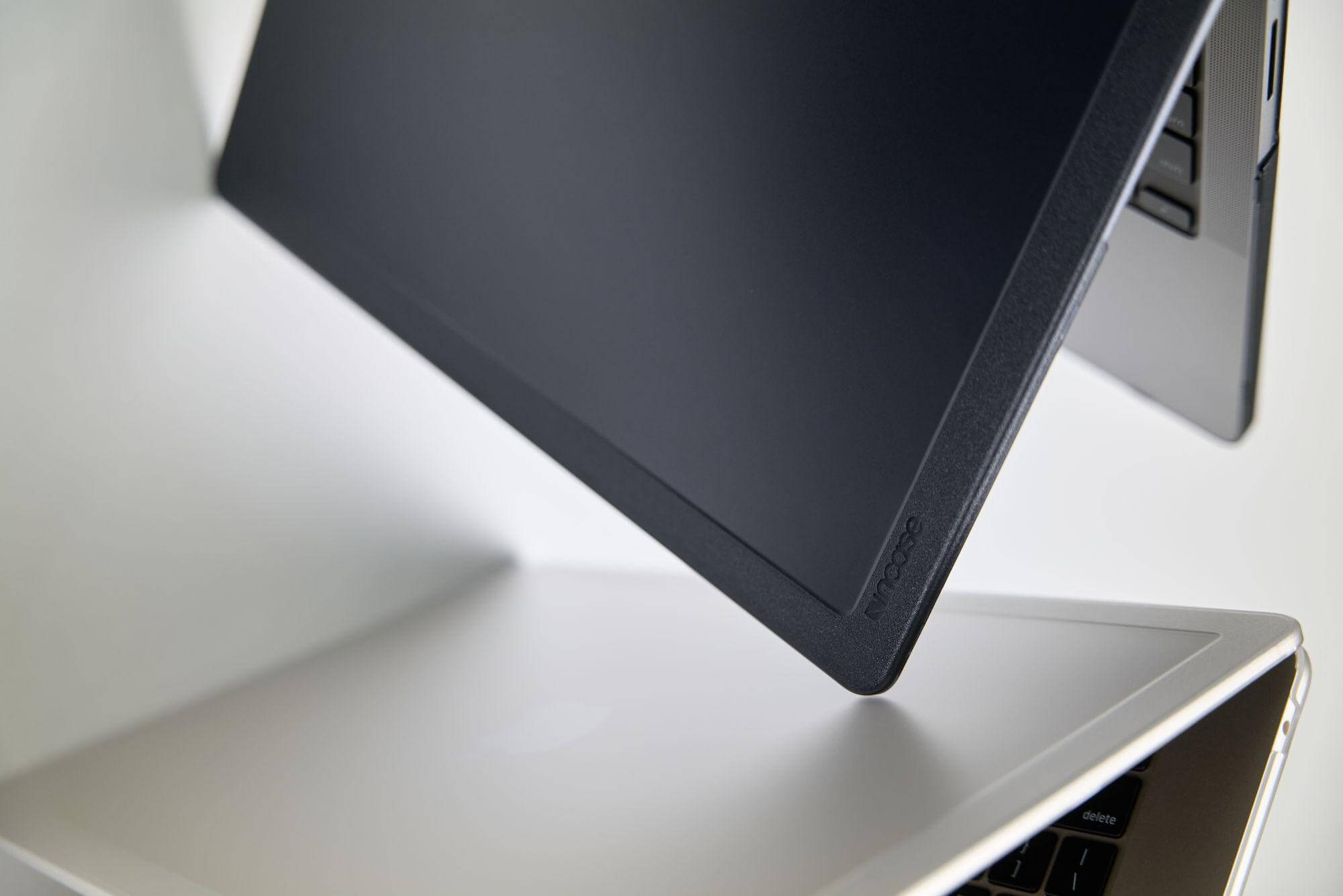Zwei Laptops gestapelt. Der obere Laptop ist dunkel, der untere Laptop ist hellgrau. Untere zeigt die Tastatur.