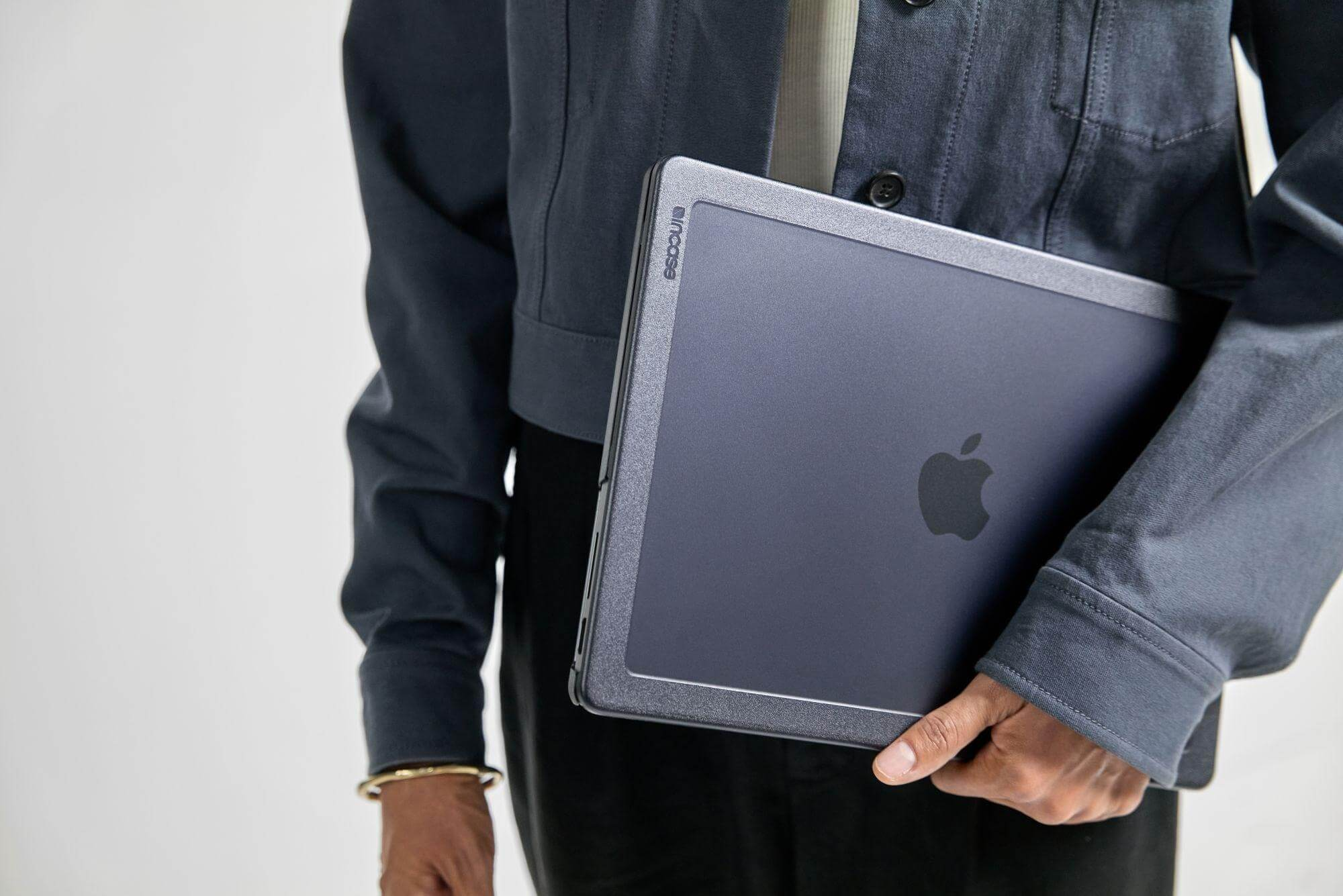 Frau hält Laptop in Hülle. Laptop hat Apple Logo.