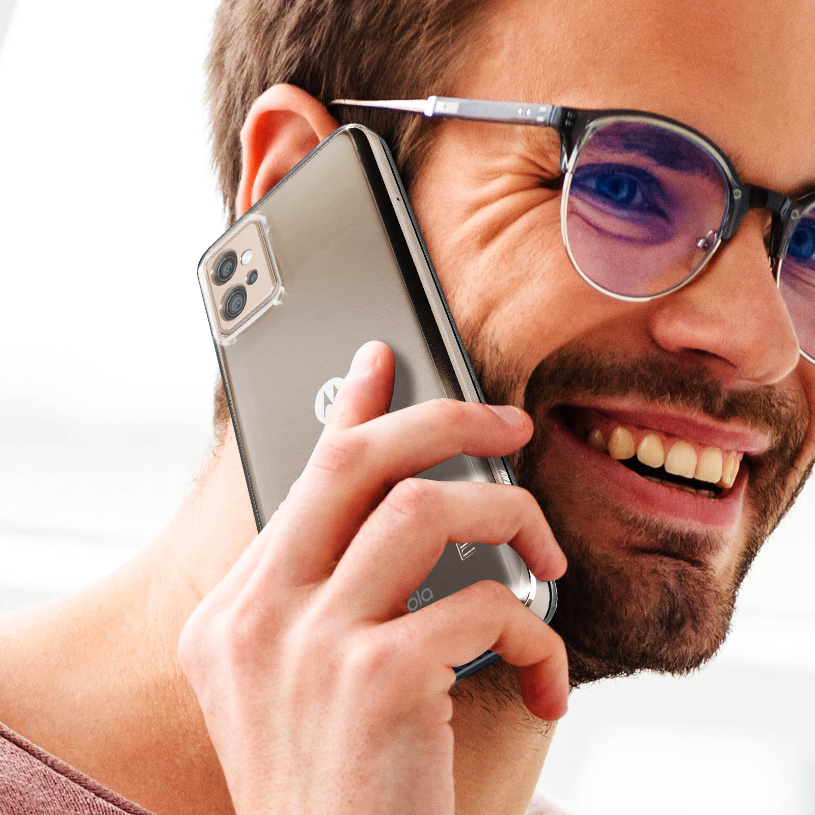 Un uomo sorridente mentre tiene un telefono all'orecchio. Indossa occhiali e una custodia trasparente.