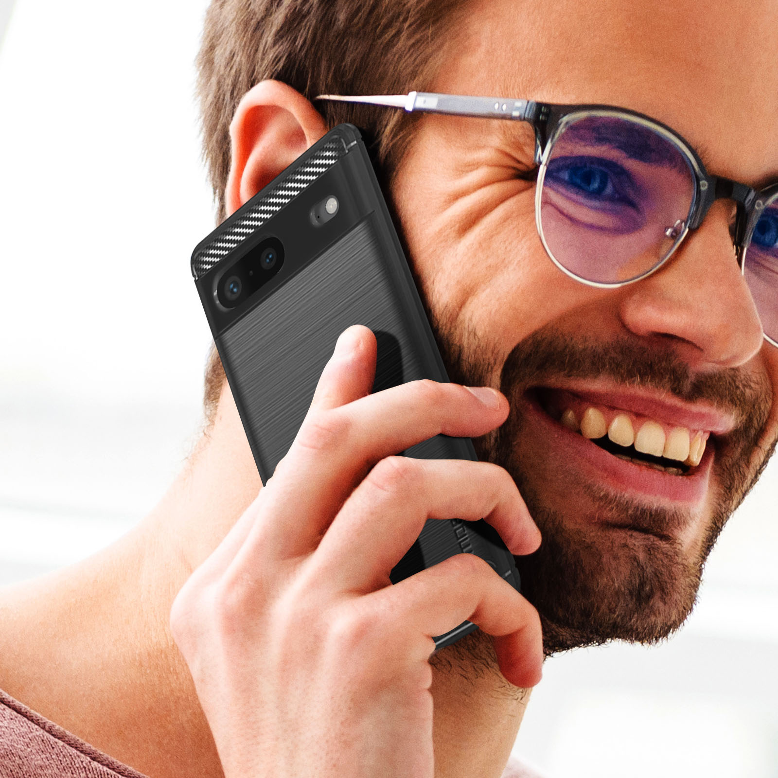 Een man houdt een zwarte telefoon met een hoesje vast. Hij glimlacht en draagt een bril.