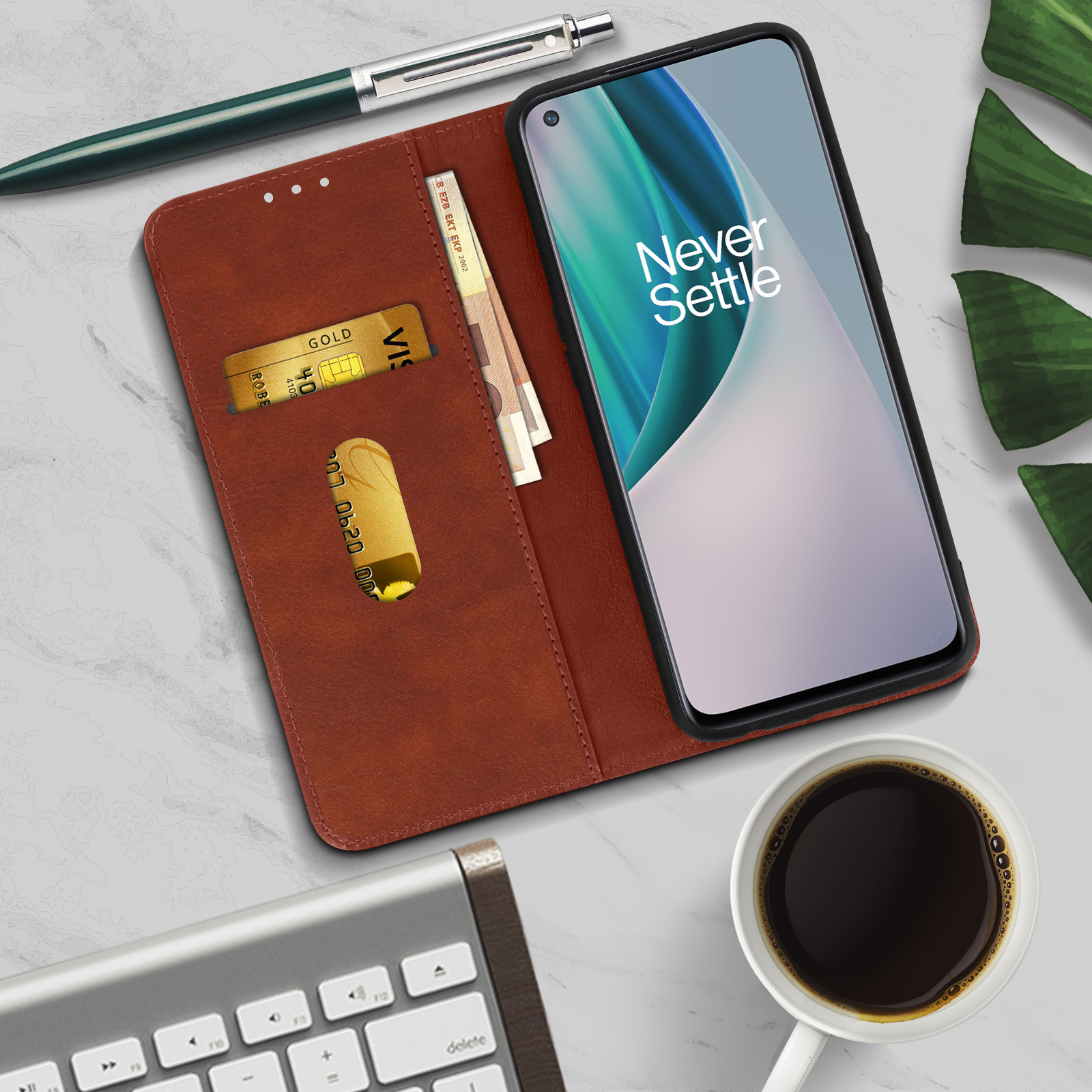 Telefono in custodia a portafoglio in pelle marrone, con carte di credito e contanti. Penna, caffè e tastiera nelle vicinanze.