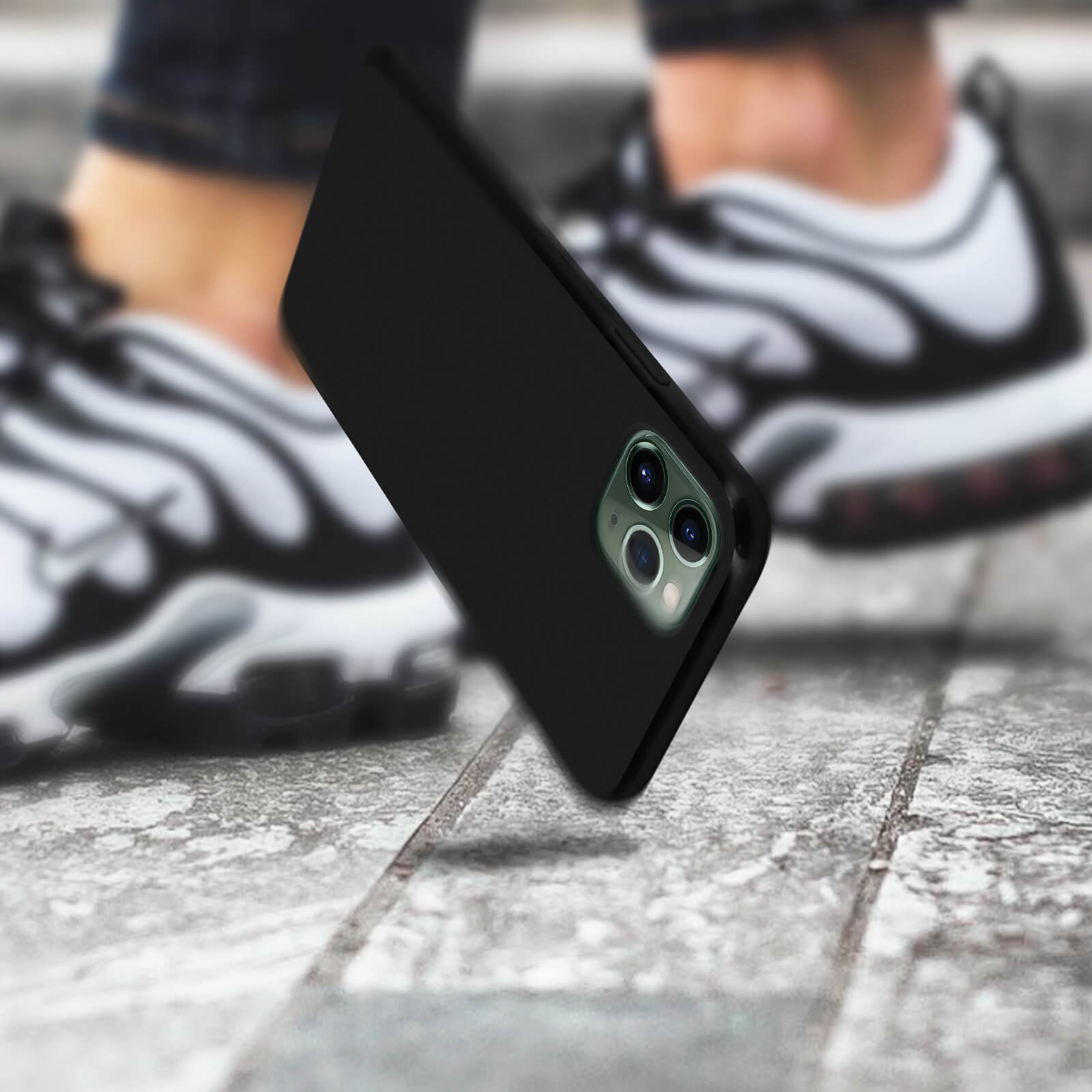 Custodia nera per telefono, leggermente inclinata, con la fotocamera rivolta verso lo spettatore, su una superficie di cemento.