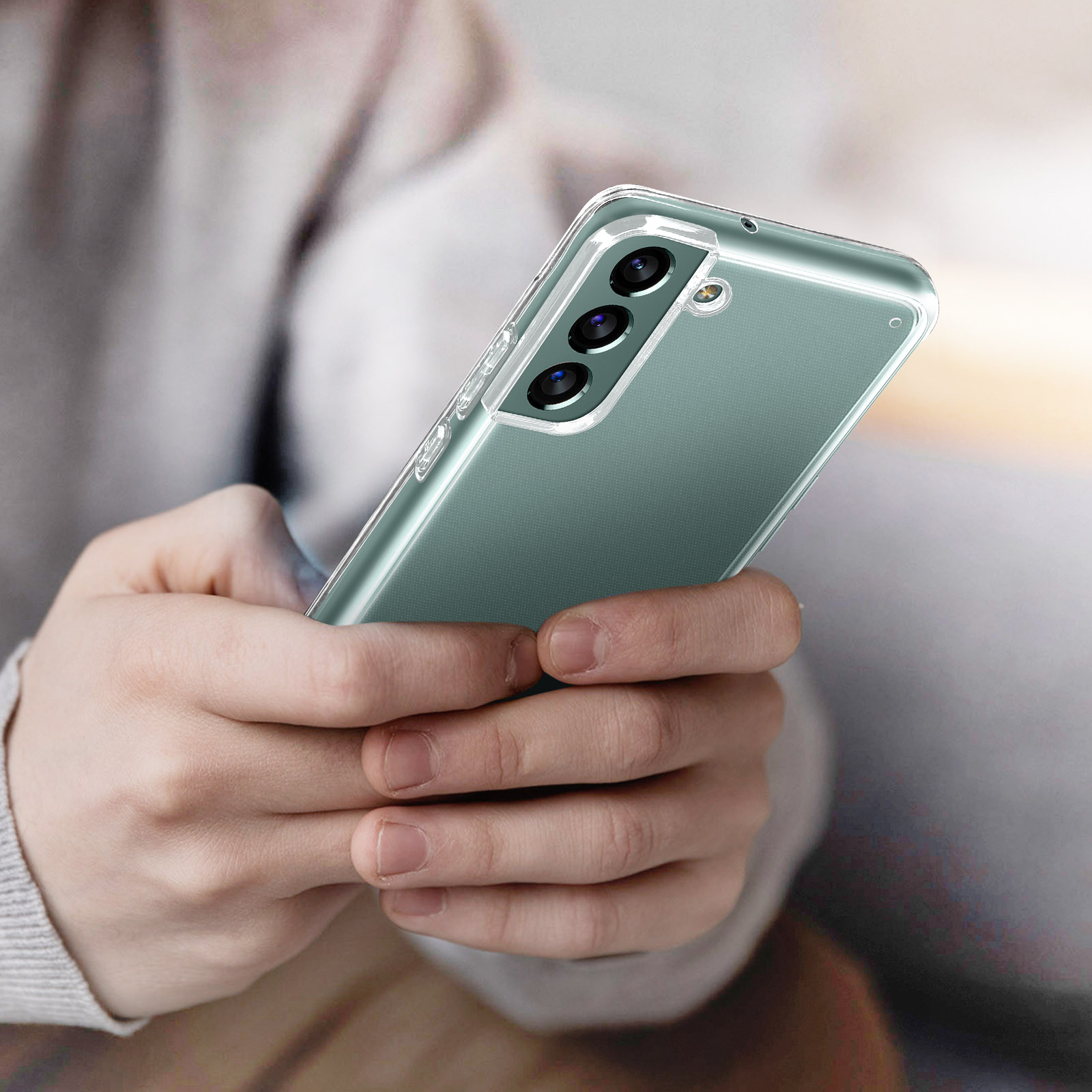 Persona che tiene in mano un telefono. Il telefono ha una custodia trasparente con retro verde.