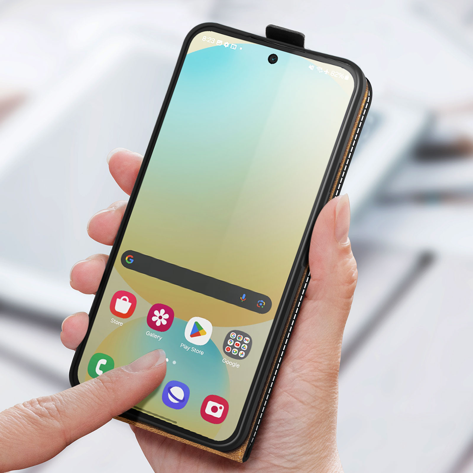 Mano che tiene il telefono in una custodia marrone. Schermo del telefono che mostra le icone delle app. Dito che tocca il display.