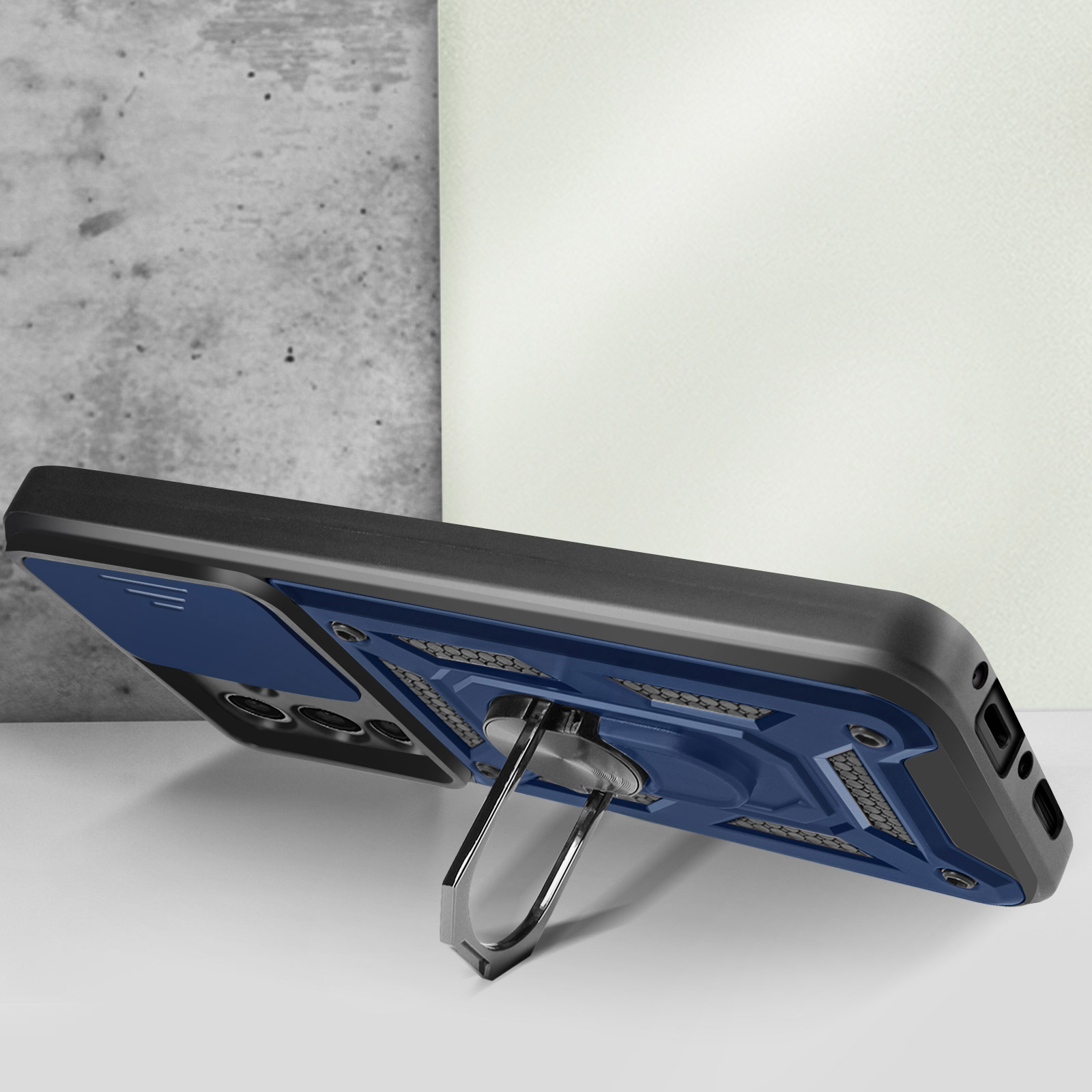 Een blauwzwarte telefoonhoes met ringstandaard. De telefoon ligt op een wit oppervlak.