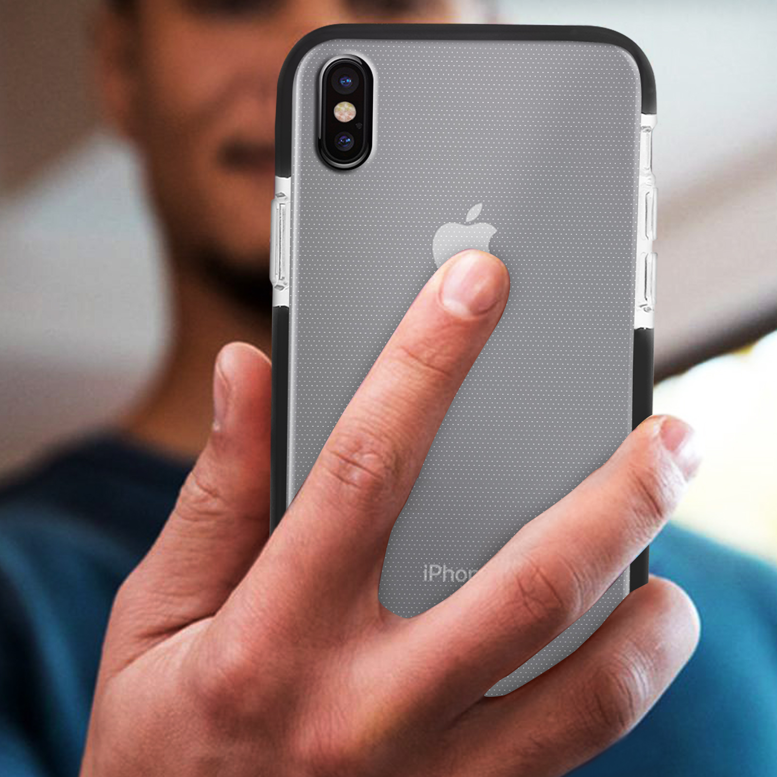La mano di una persona che tiene un telefono in una custodia trasparente, con il logo Apple visibile.