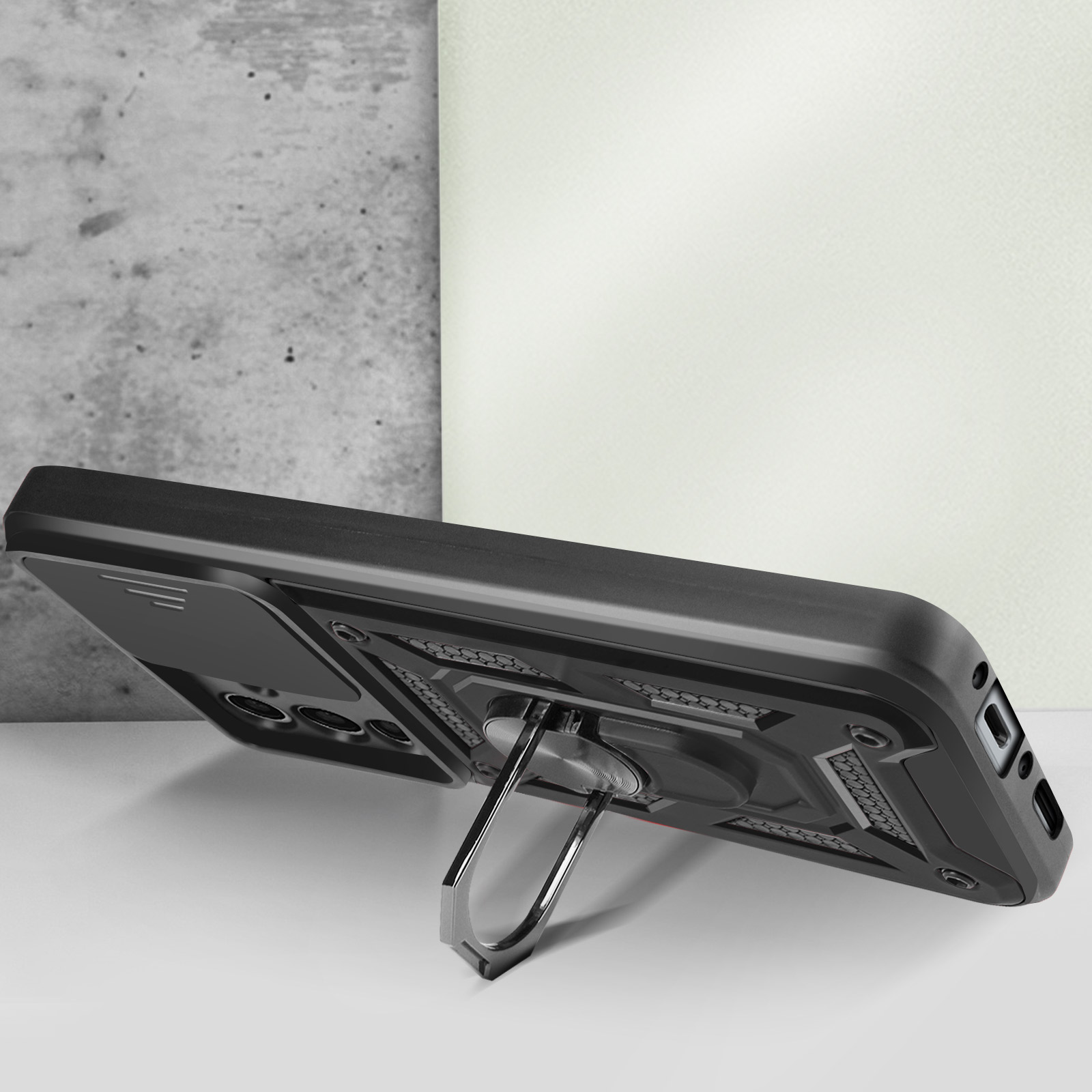 Coque de téléphone noire avec porte-anneau. La coque est posée sur une table.