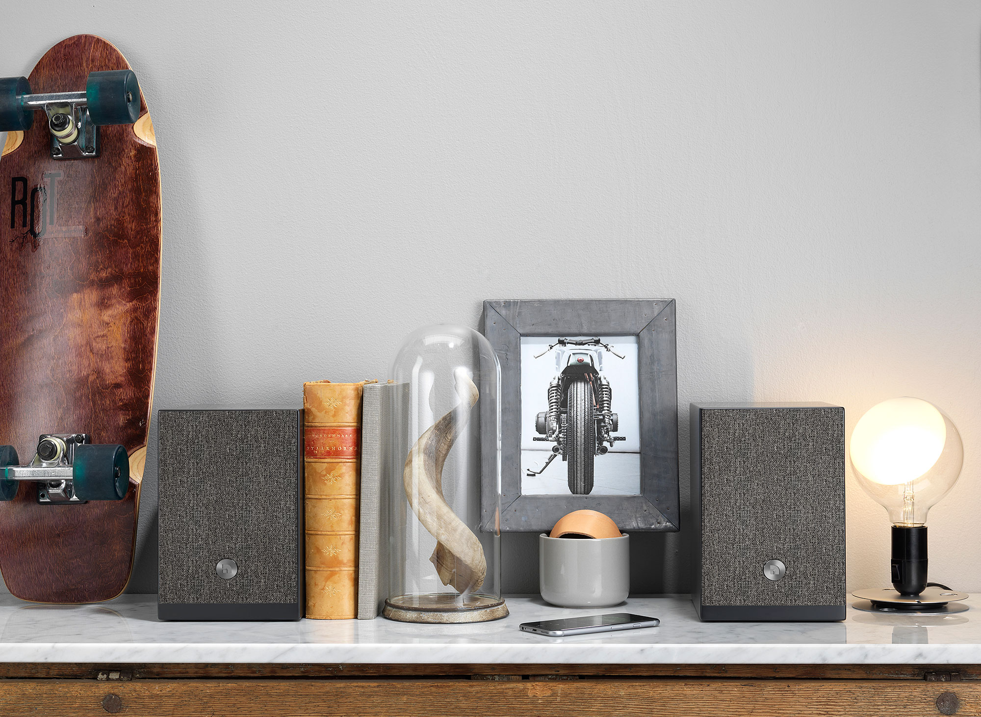 Configurazione da tavolo con altoparlanti, libri, skateboard e cornice.